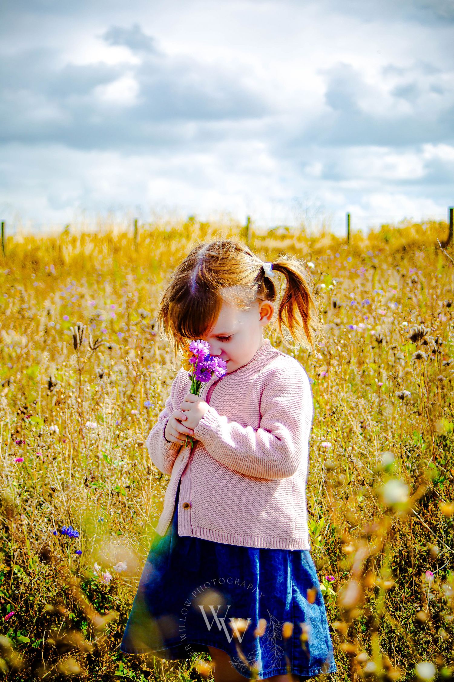 Young girl holding a small pink flower in the Rosedew Farm meadow