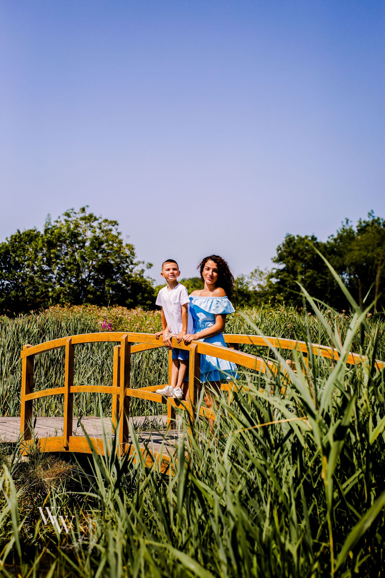Family standing together on a wooden bridge during an outdoor photoshoot at Cosmeston Lake, Penarth