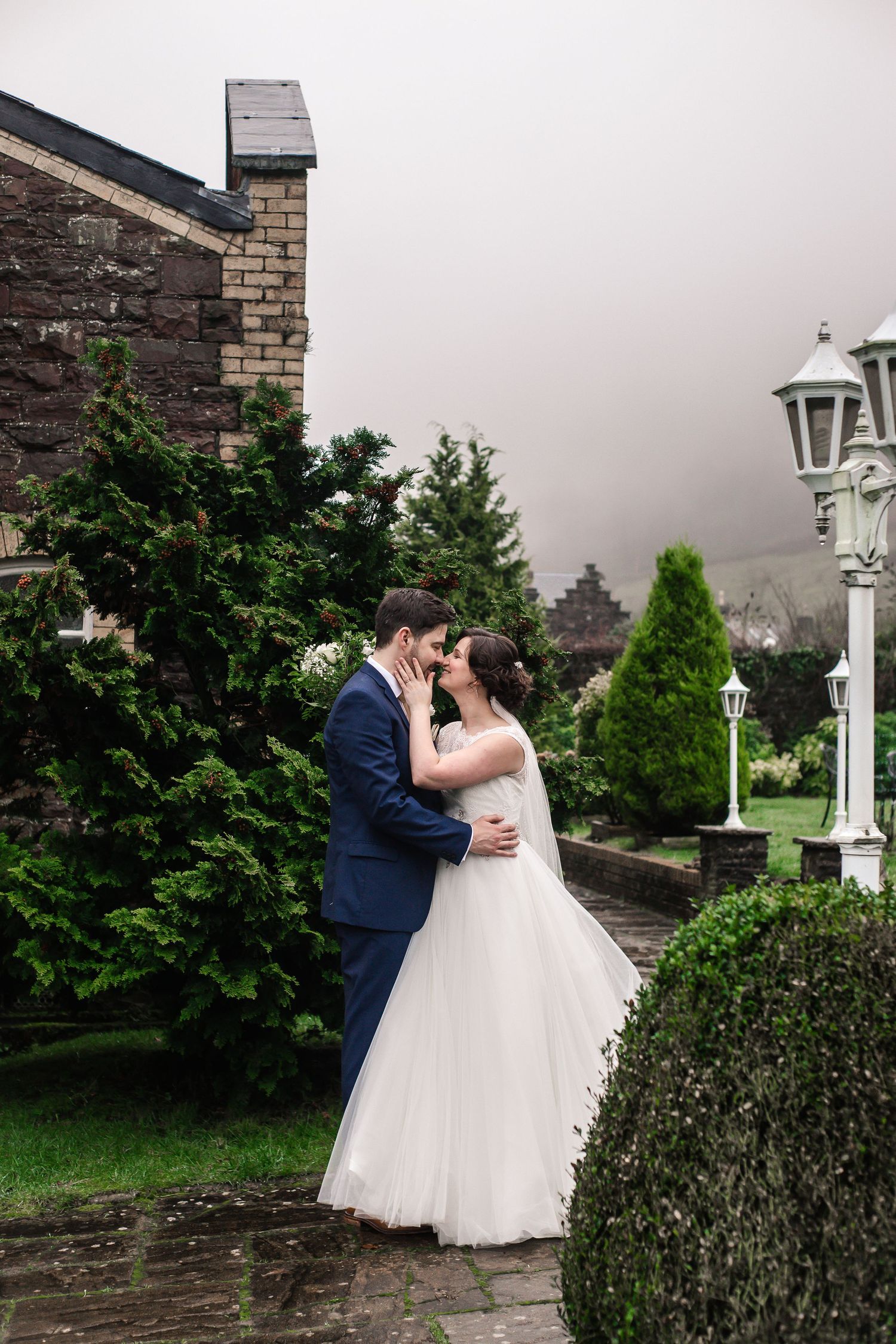 Newlywed couple embracing beside a stone wedding venue