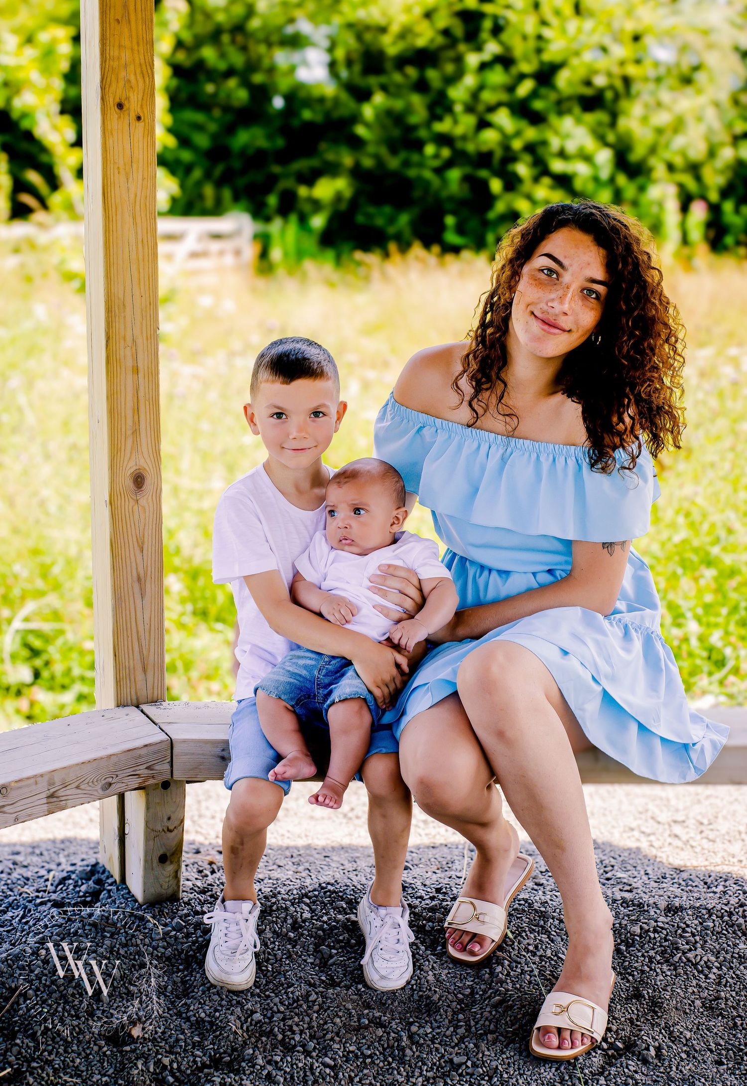 Mother seated with her two children during a sunny outdoor photoshoot at Cosmeston Lake, Penarth