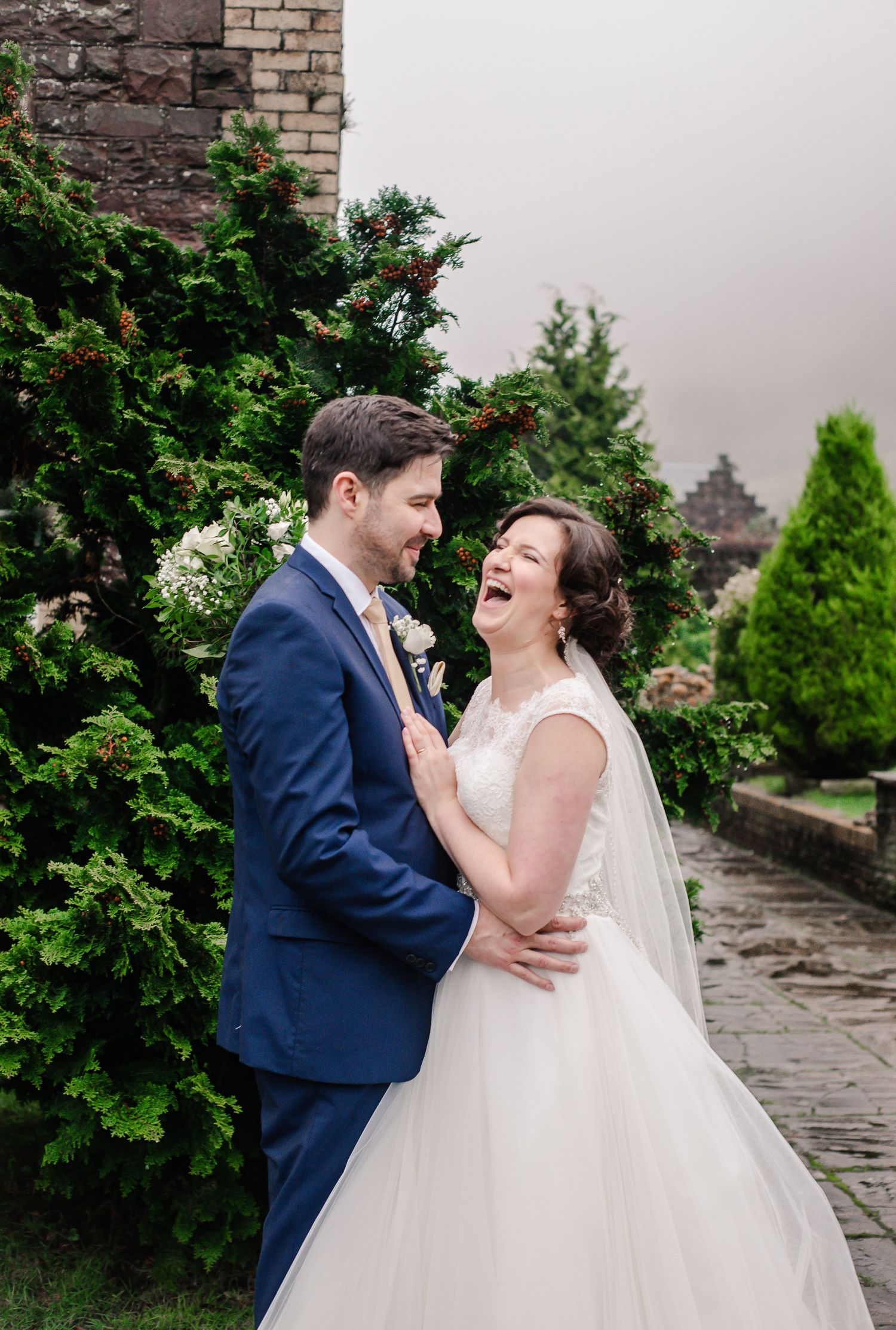 Bride and groom laughing in the Craig y Nos Castle gardens