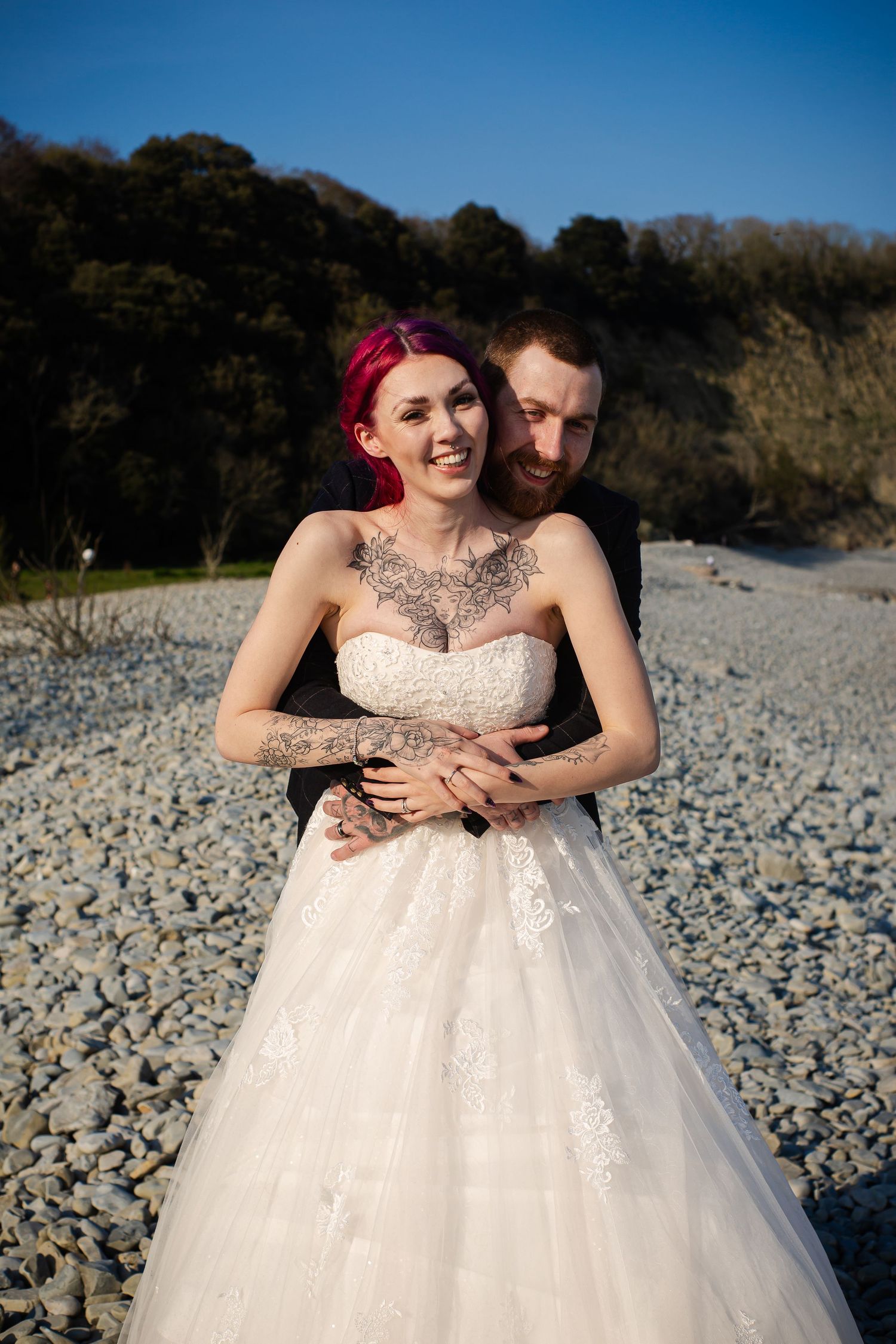 Groom embracing the bride from behind during their beach portraits