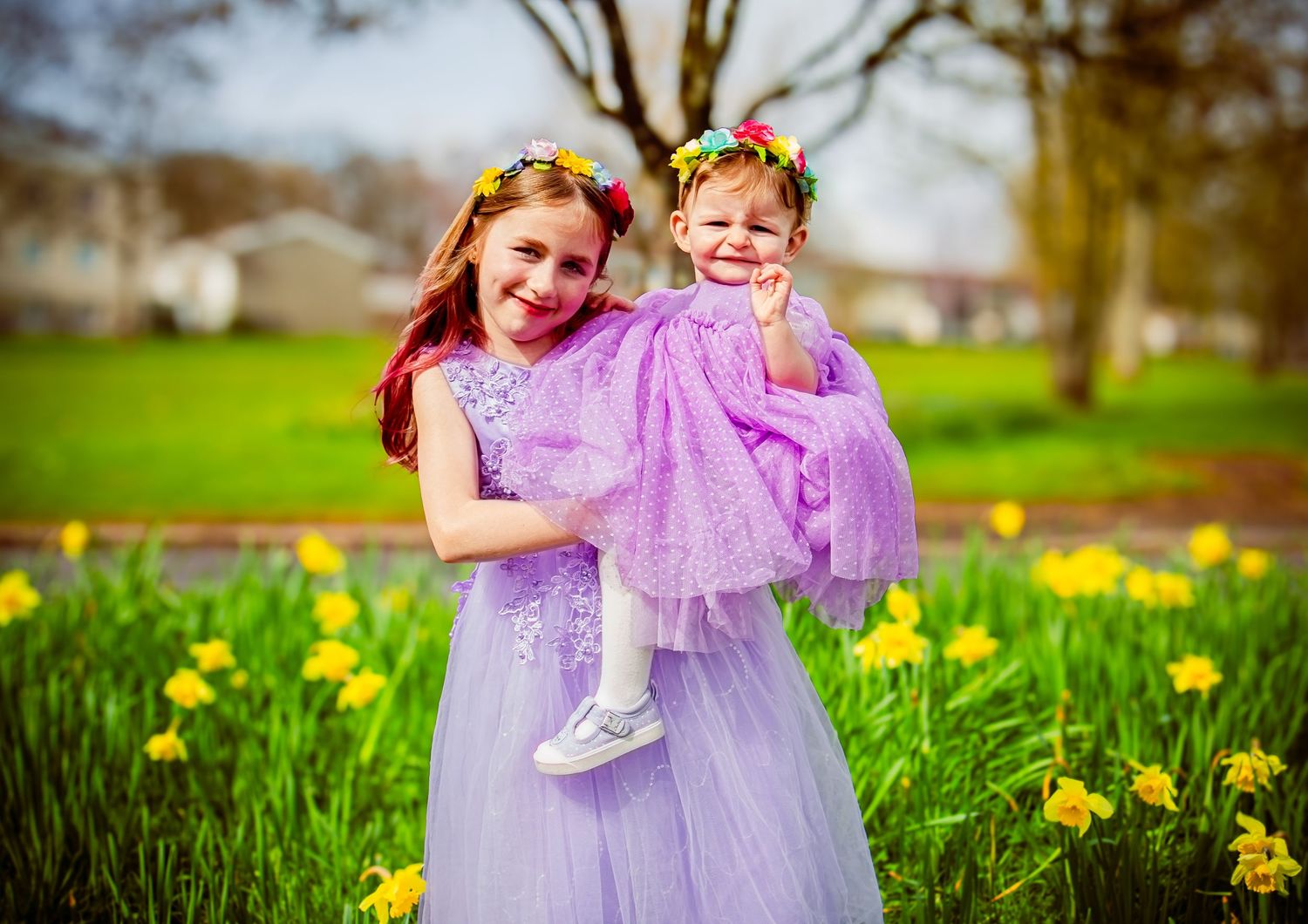 Older sister carrying her younger sister through a daffodil field