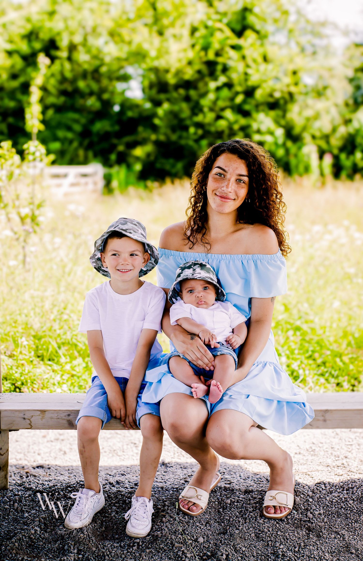 Mother seated with her two children beside a wildflower meadow at Cosmeston Lake, Penarth