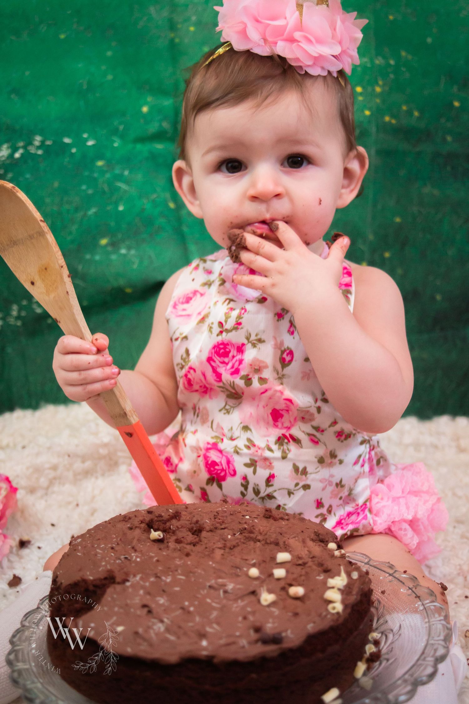 Baby girl tasting chocolate cake at her first-birthday cake smash