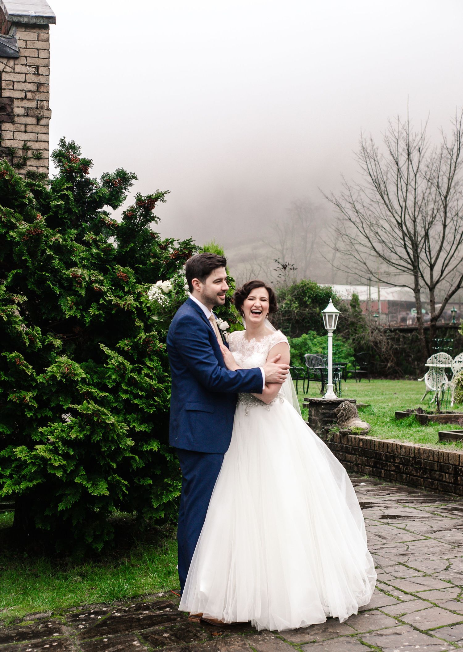 Bride and groom laughing in the Craig y Nos Castle gardens