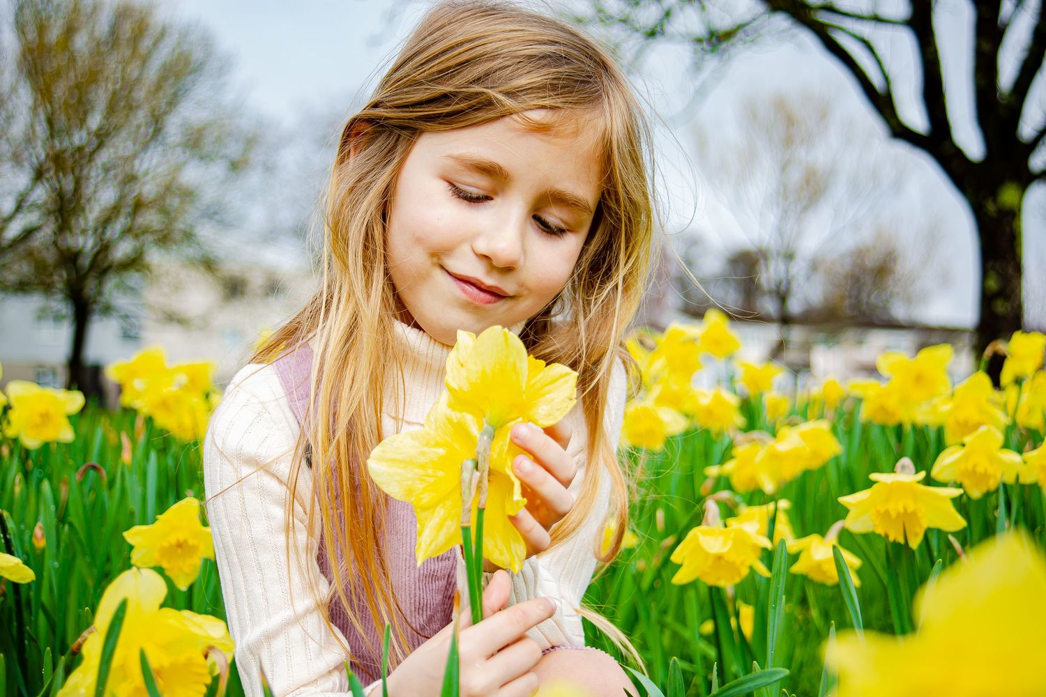 Girl gently holding a yellow daffodil during a spring portrait session