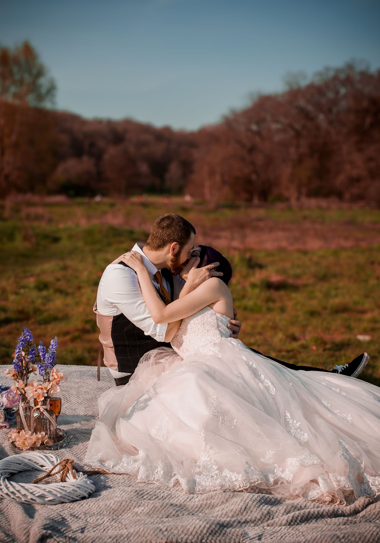 Bride and groom sharing a quiet kiss on a picnic blanket