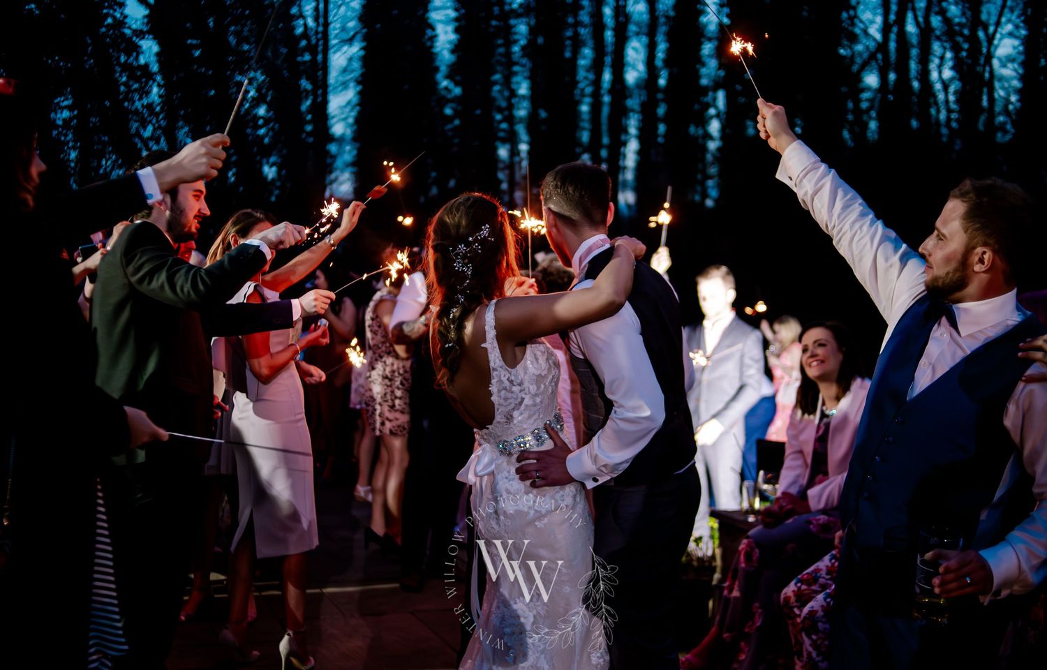 Newlyweds celebrating beneath sparklers with their wedding guests
