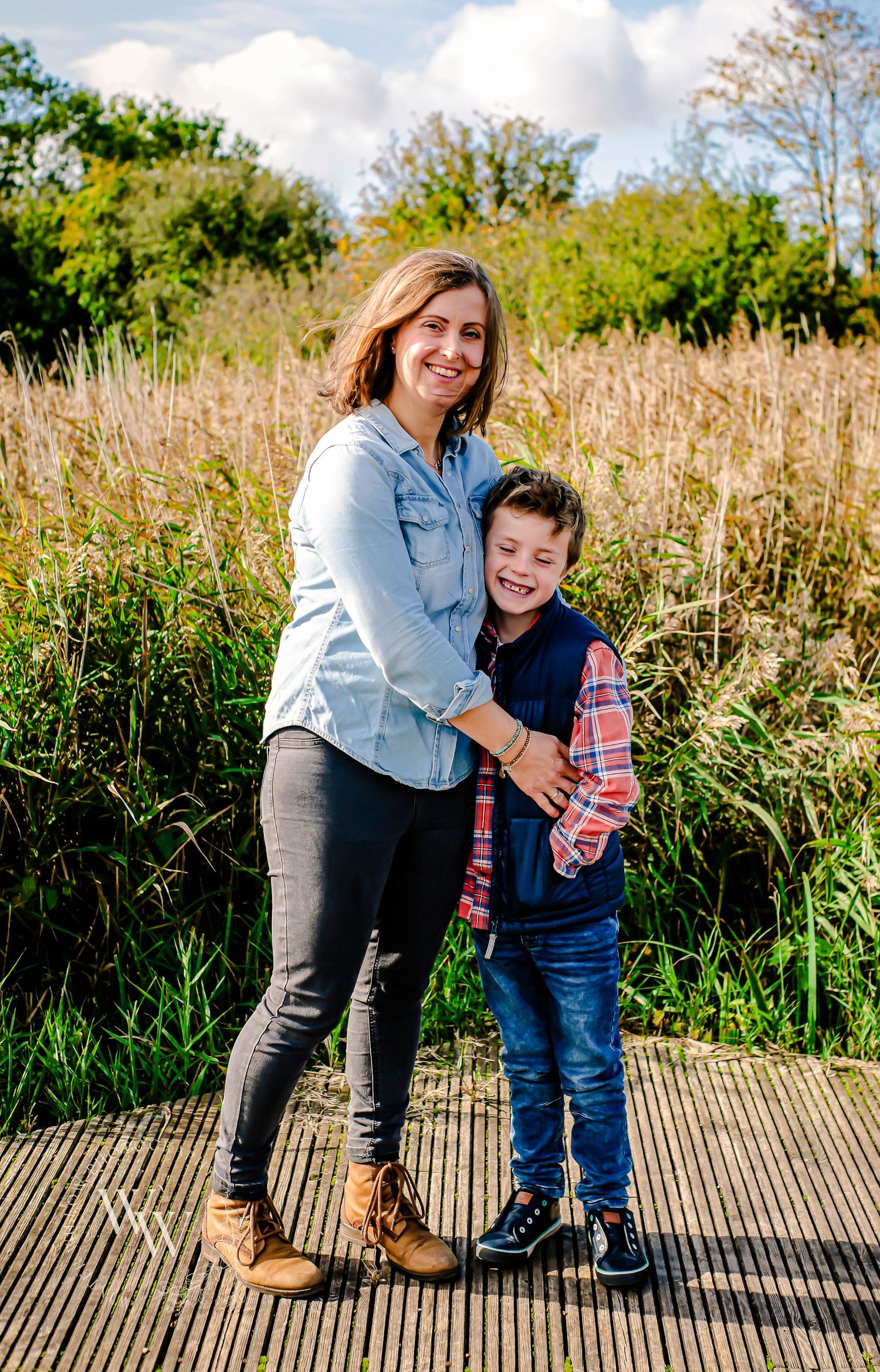 Mother embracing her young son beside the reeds at Cosmeston Lakes, Penarth