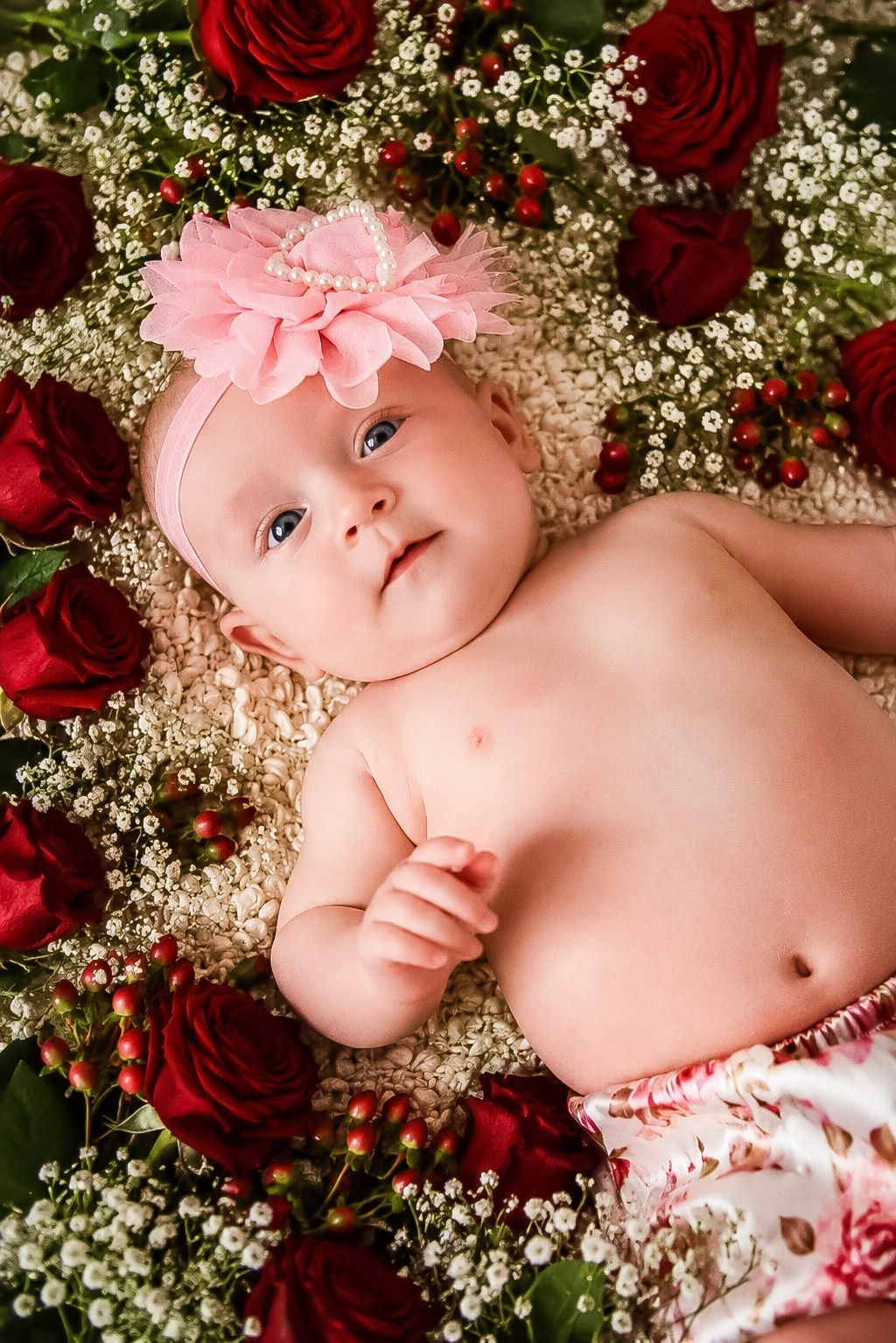 Close-up floral portrait of a baby girl wearing a large pink headband