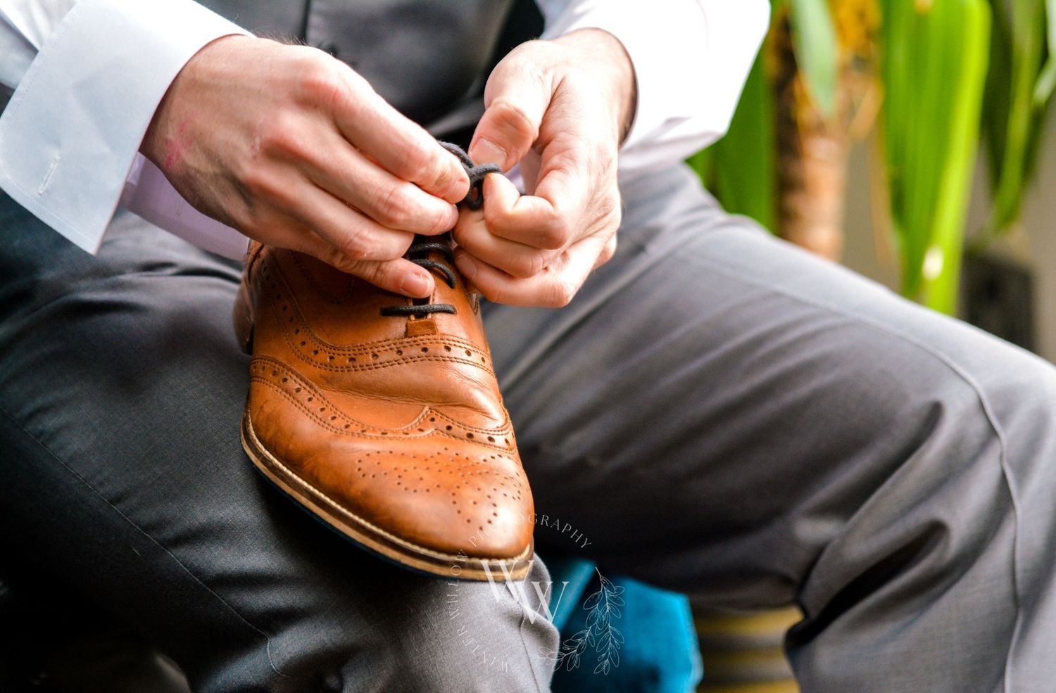Groom tying the laces of his brown wedding shoes
