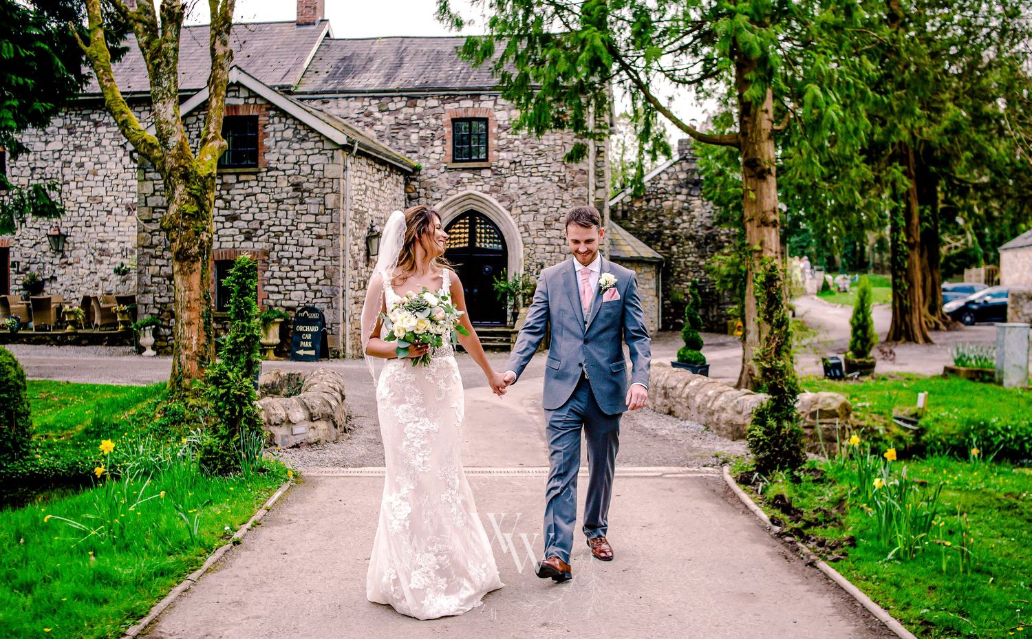 Bride and groom smiling while walking through the Pencoed House grounds