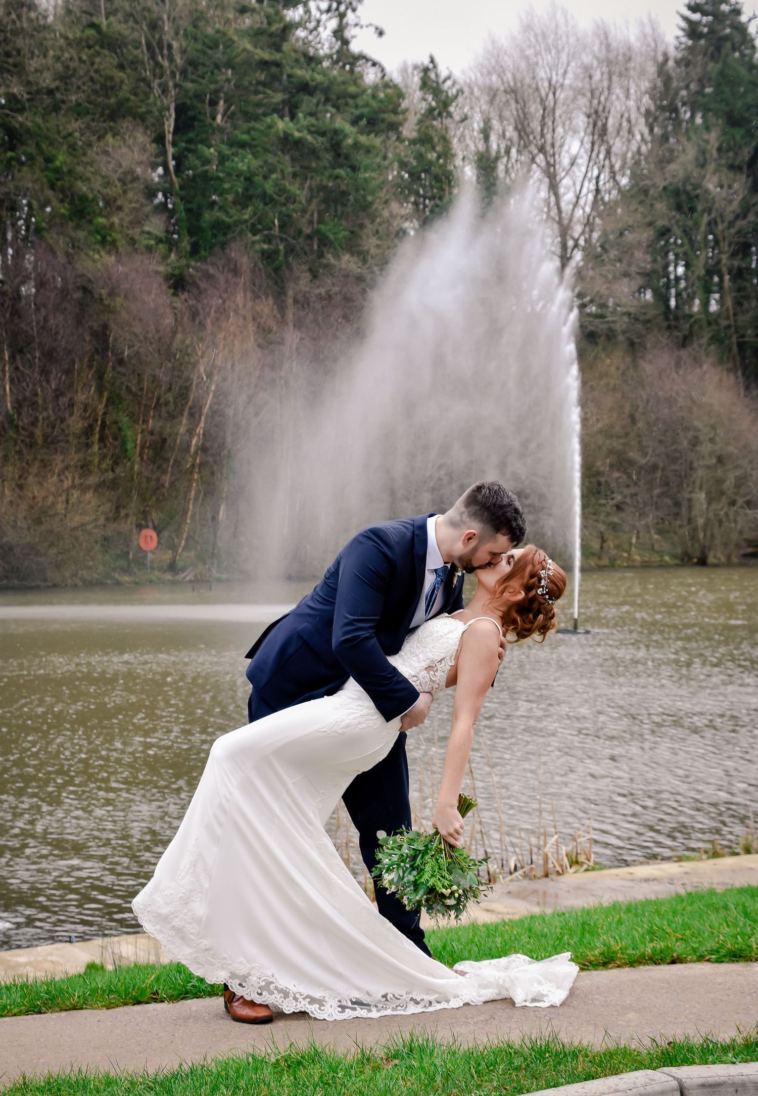 Groom dipping his bride beside the waterfall at Canada Lodge in Cardiff