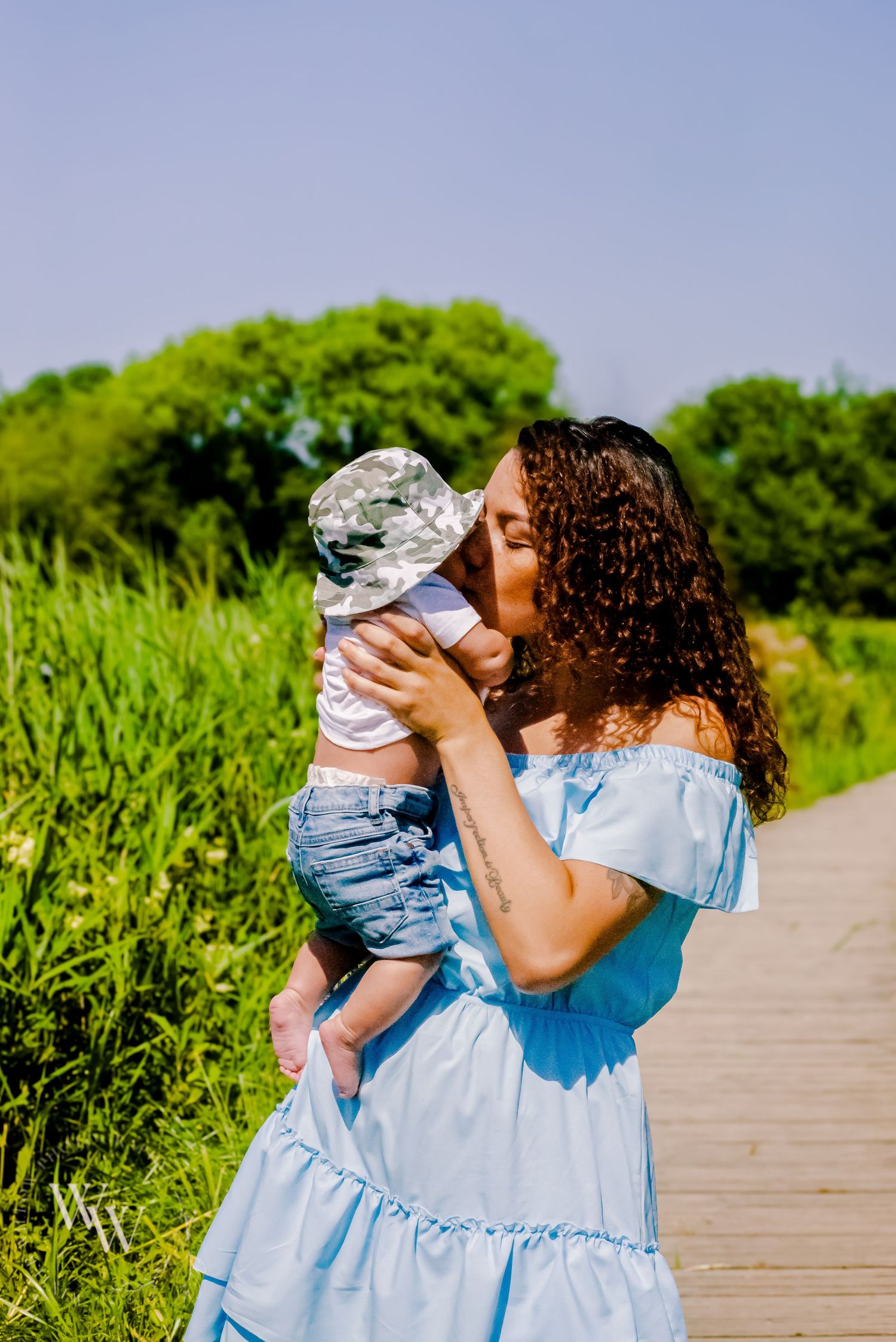 Mother kissing her baby during a relaxed outdoor family photoshoot at Cosmeston Lake, Penarth