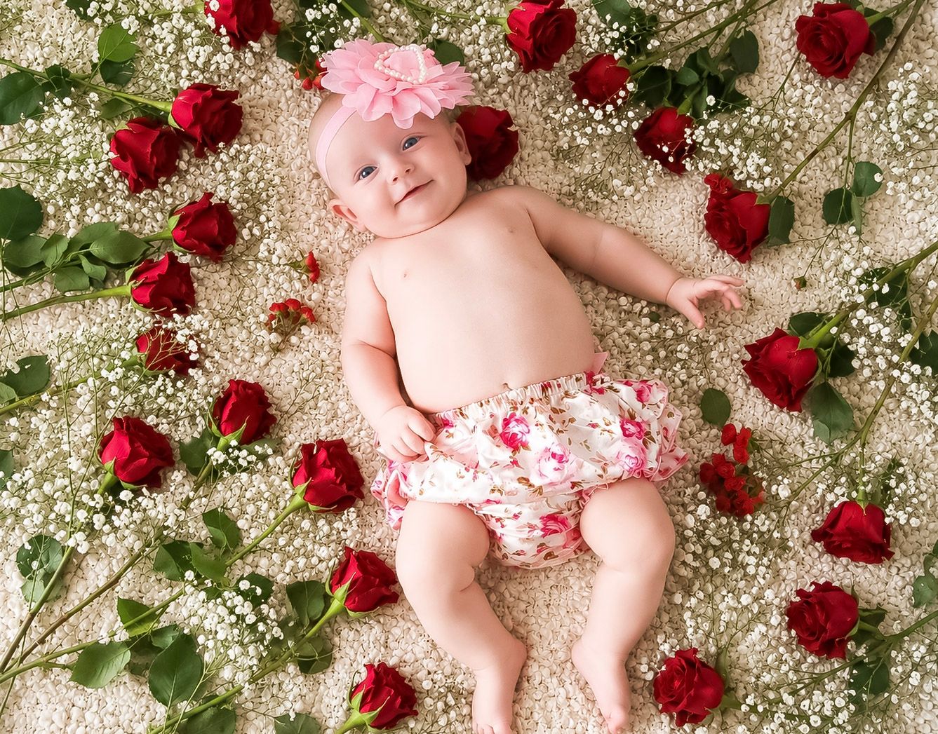 Full-length baby portrait arranged among roses and delicate white flowers
