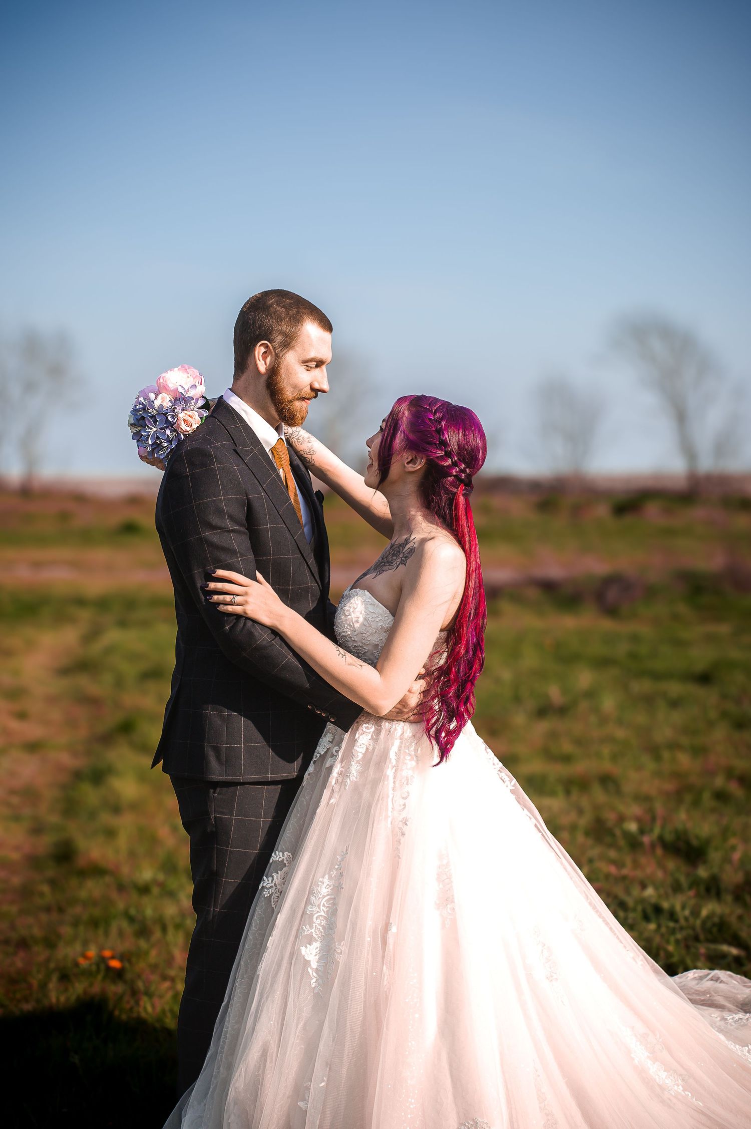 Groom holding a flower while embracing his bride outdoors