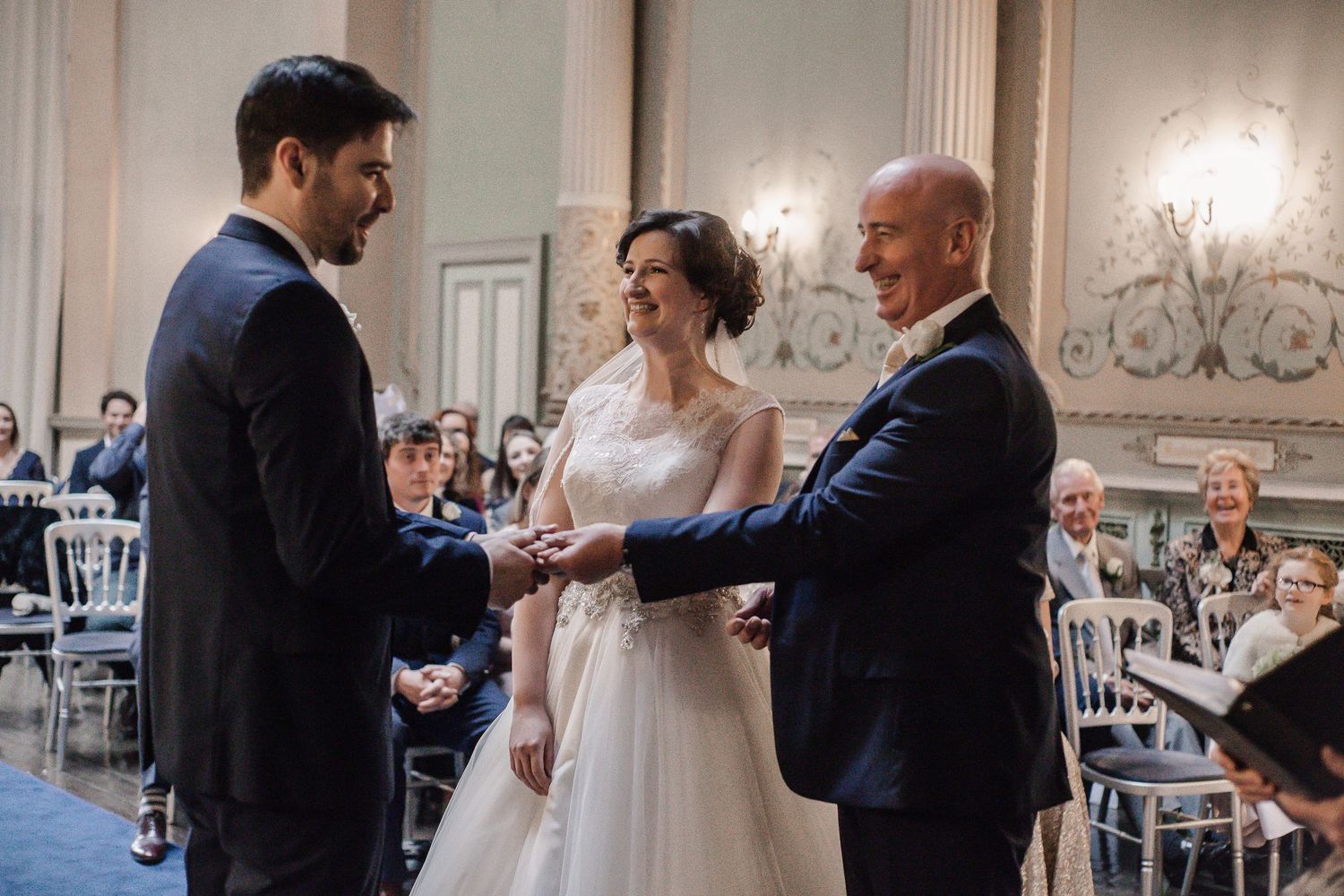 Bride’s father placing her hand into the groom’s during the ceremony inside Craig y Nos Castle