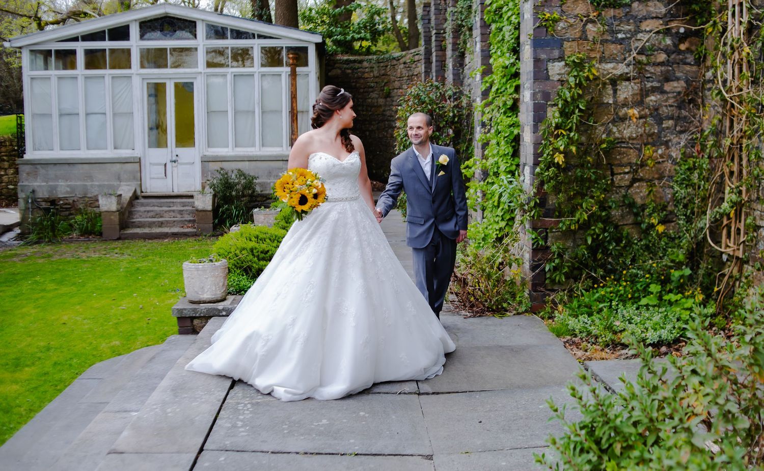 Bride and groom walking hand and hand with garden backdrop, Court Colmon, Bridgend