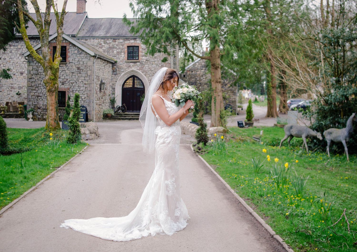 Bride walking through a garden with her lace train flowing behind her