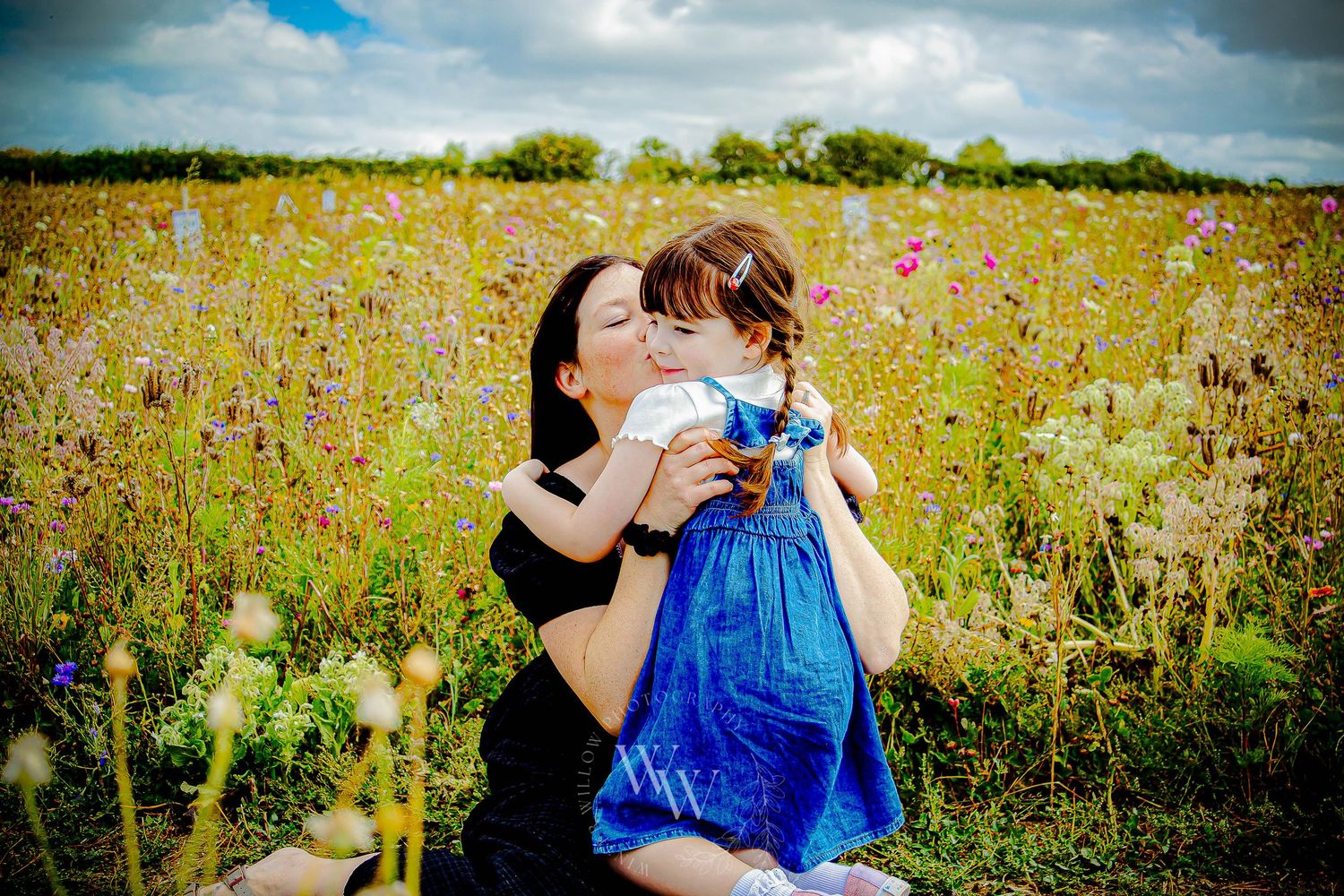 Mother kissing her young daughter in the Rosedew Farm flower meadow