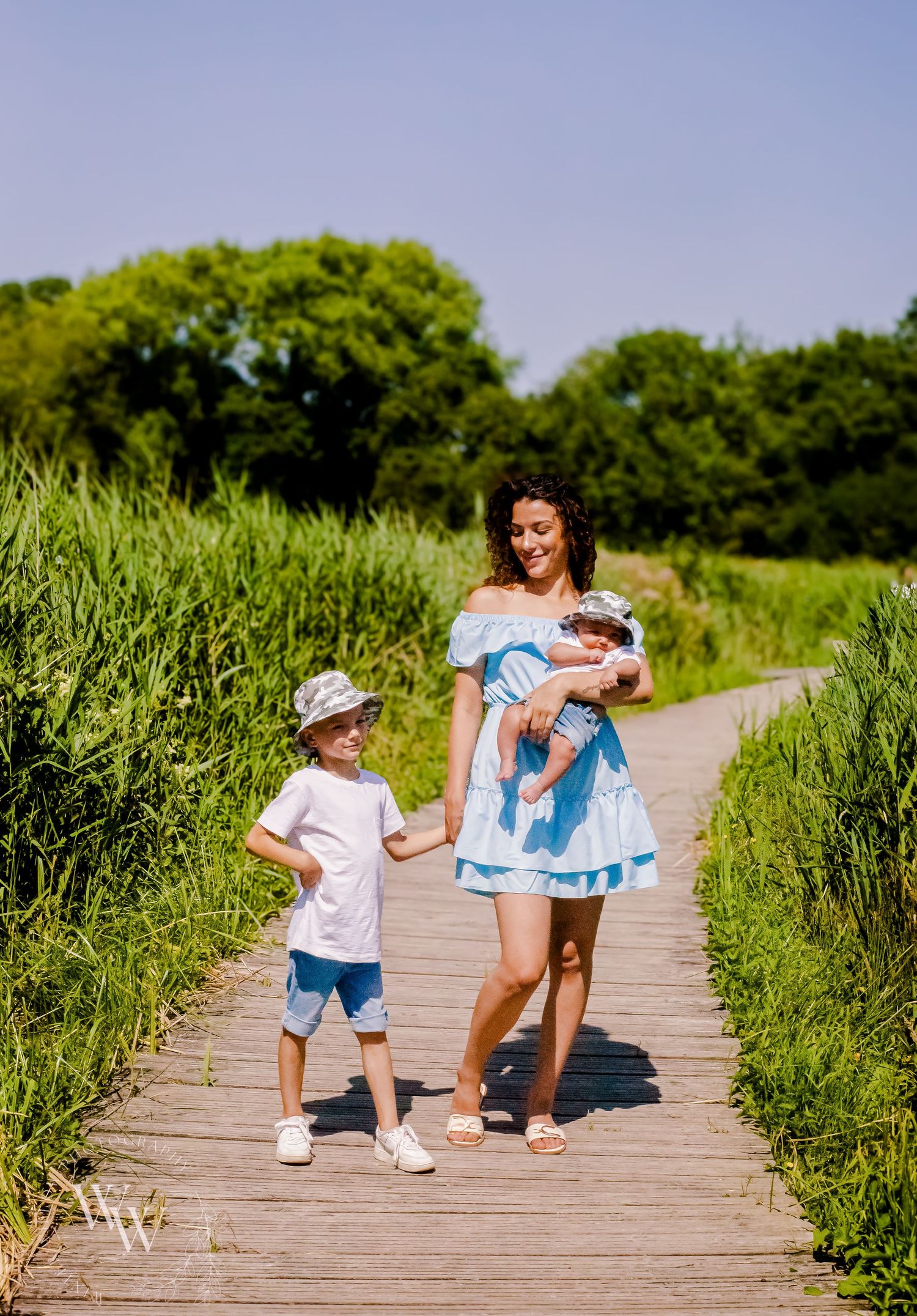 Mother walking with her two children along a summer nature trail at Cosmeston Lake, Penarth