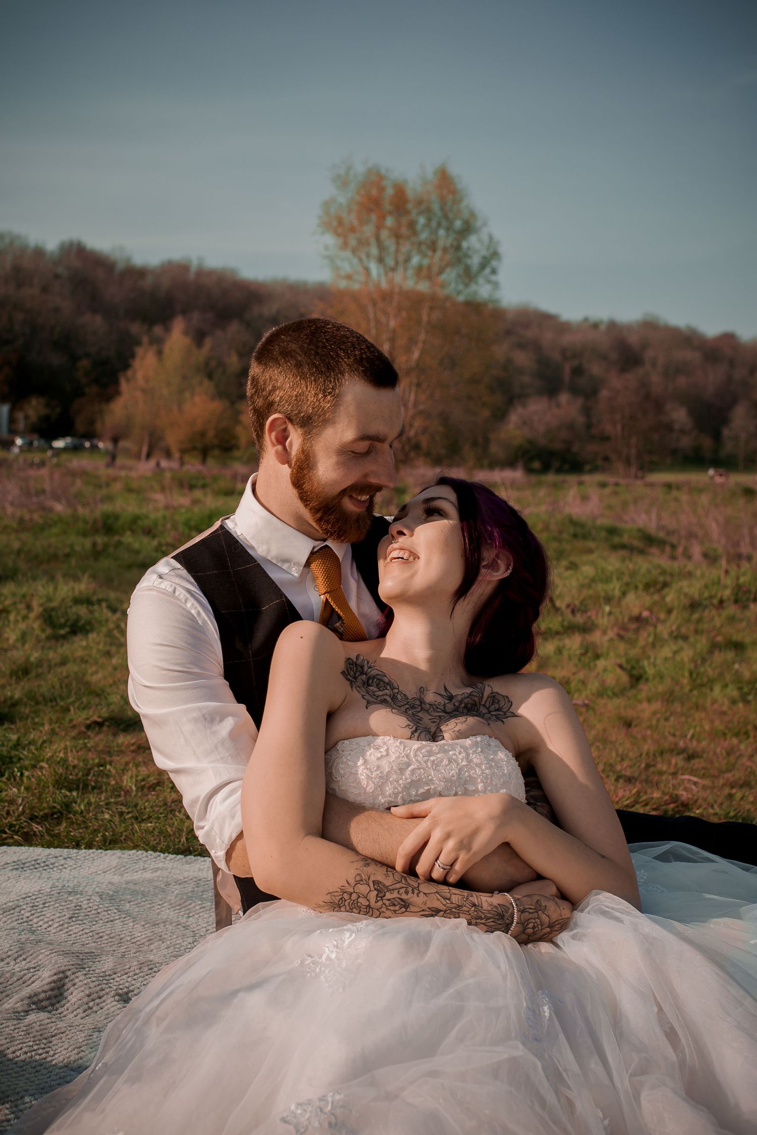 Groom embracing the seated bride during their romantic picnic