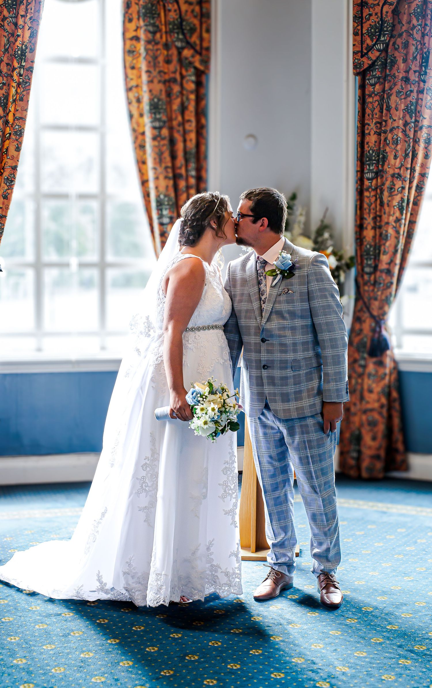Newlyweds embracing beside the window in the St David’s Suite at Cardiff City Hall