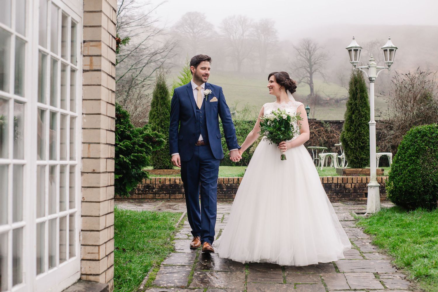 Newlyweds walking through the grounds of Craig y Nos Castle