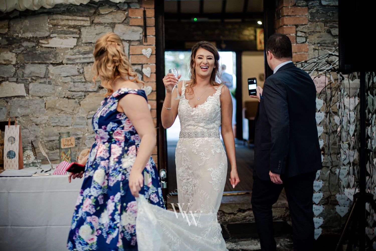 Smiling bride greeting guests outside Pencoed House in Bridgend