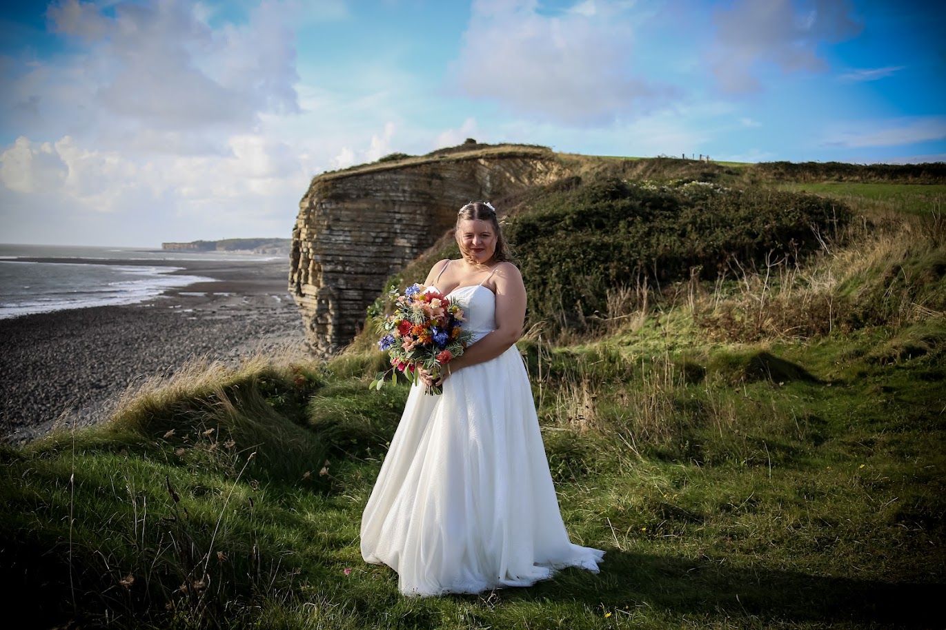 Bride holding her bouquet on dramatic South Wales coastal cliffs at Rosedew Farms