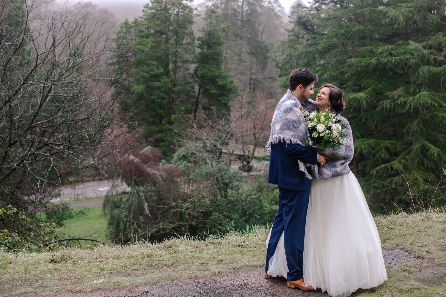 Bride and groom embracing during relaxed woodland wedding portraits