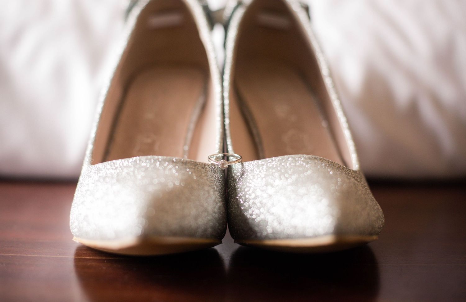 Pair of sparkling bridal shoes photographed before the wedding holding engagement ring