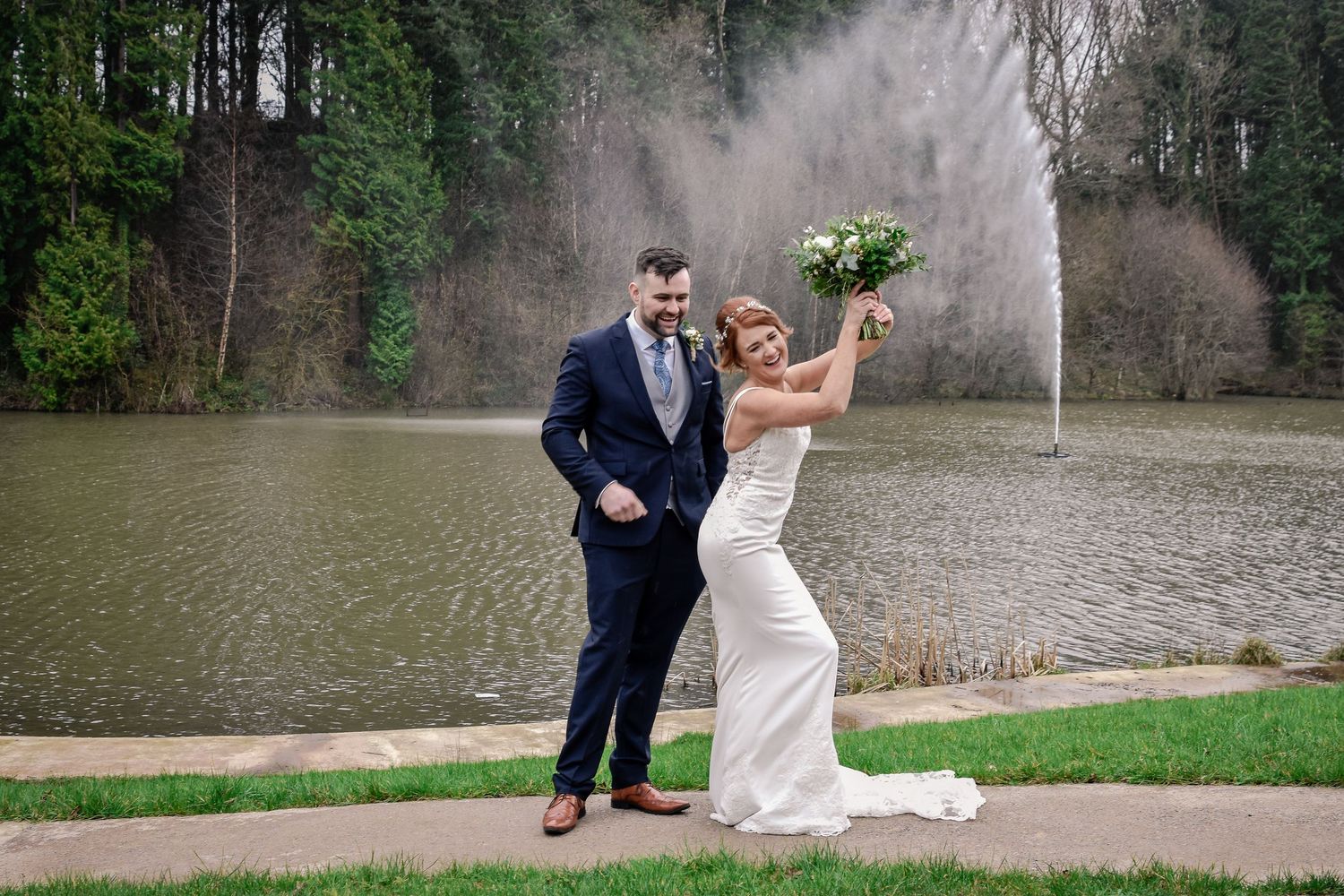 Bride playfully holding up her bouquet beside the Canada Lodge lake