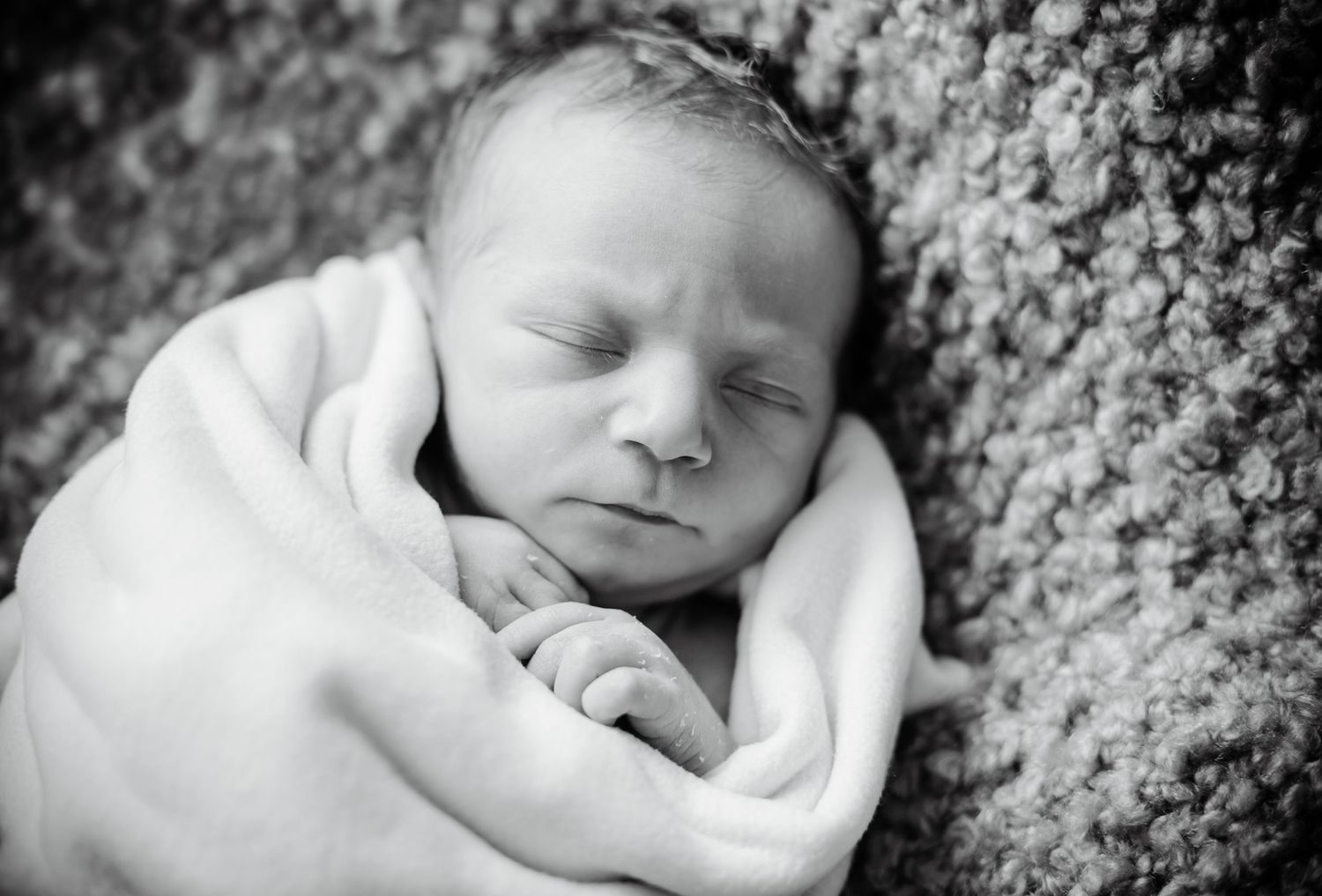Black and white portrait of a swaddled newborn baby boy