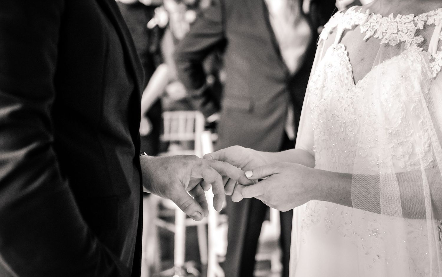 Black and white close-up of the bride placing a wedding ring on the groom