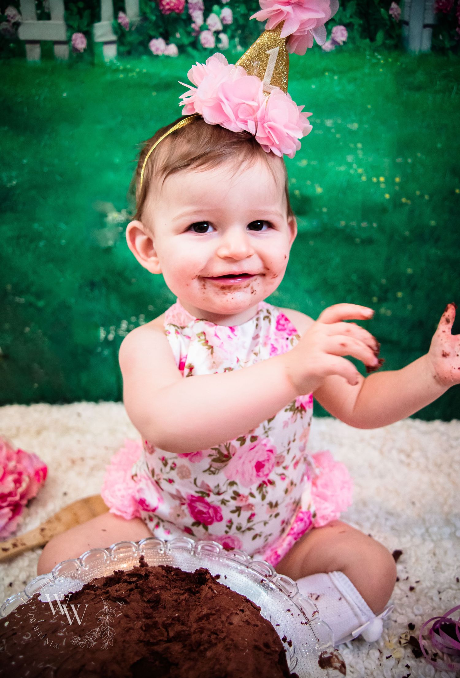 Baby girl celebrating her first birthday during a chocolate cake smash