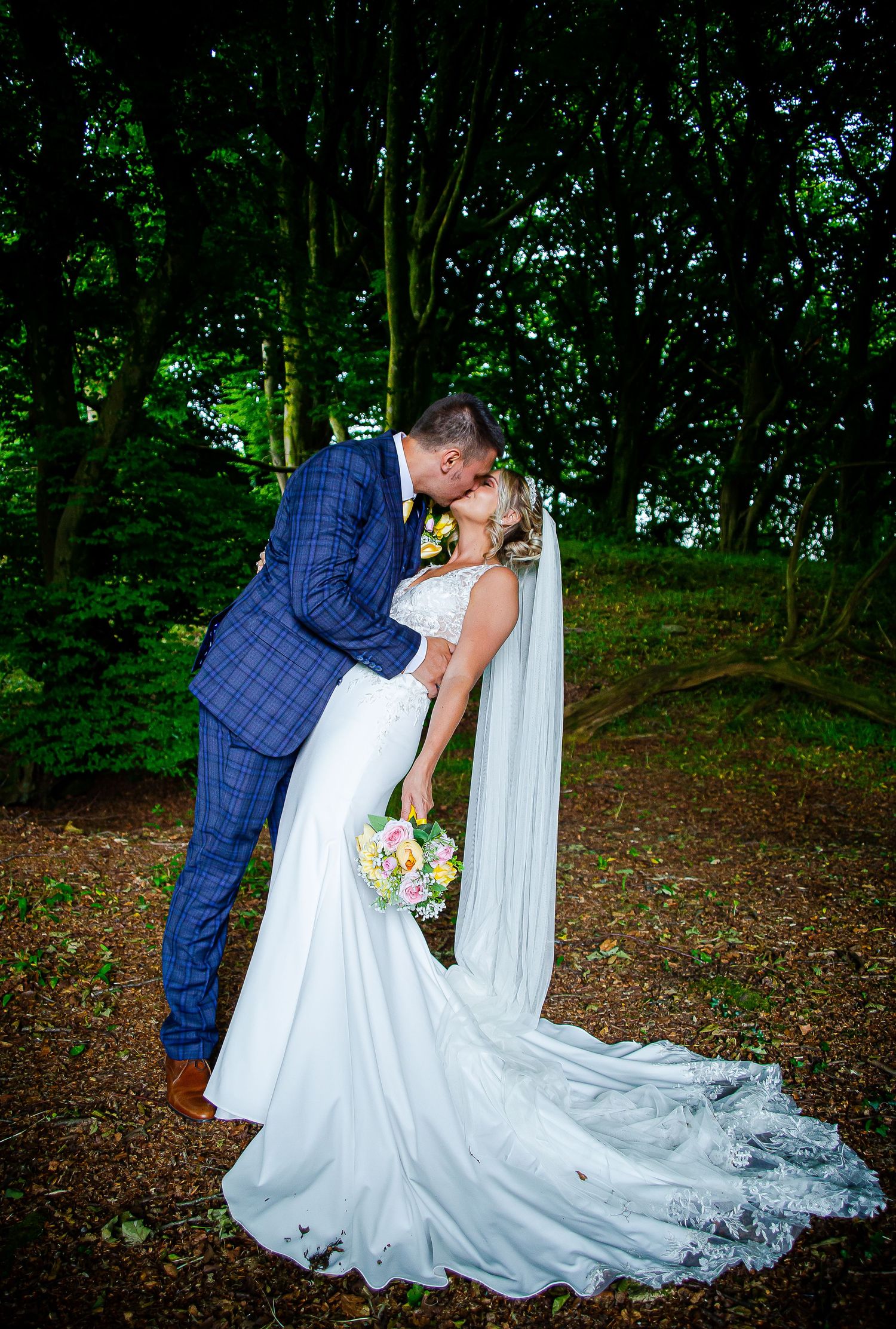 Newlywed couple embracing and kissing in the woodland at Ridgeway Golf Club