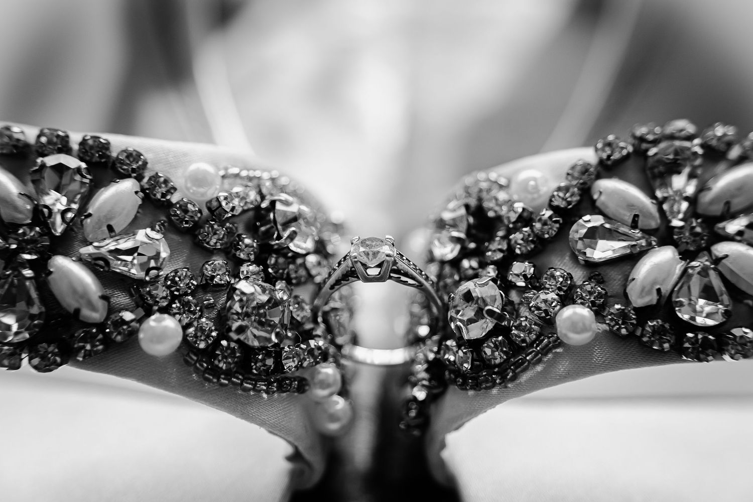 Black and white close-up of the bride’s jewelled wedding shoes with wedding ring