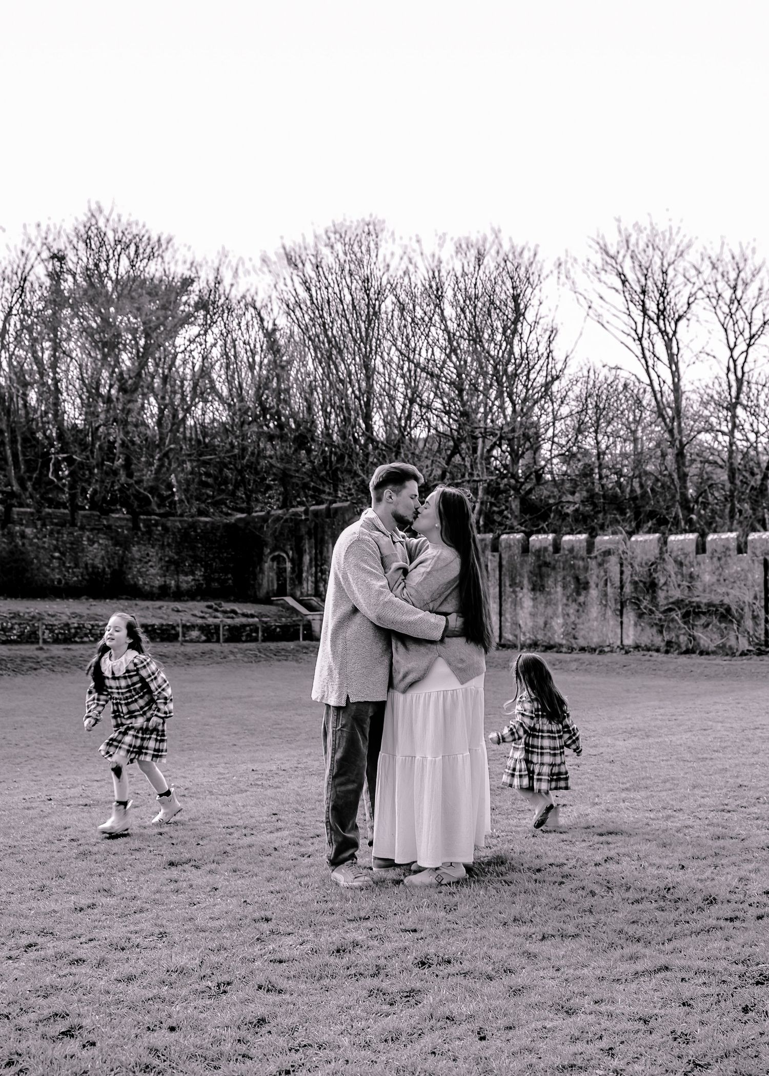 Black and white photograph of parents walking with their two daughters