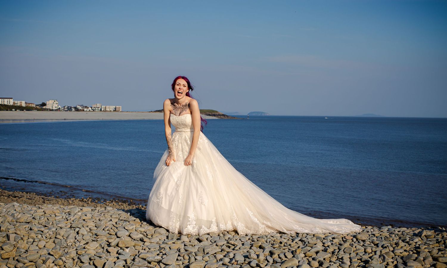 Bride standing on Porthkerry Beach with her wedding dress flowing behind her