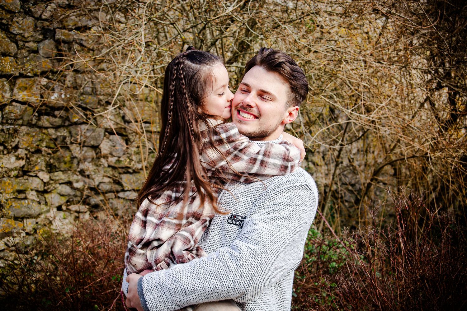 Young girl kissing her father during a relaxed family photoshoot