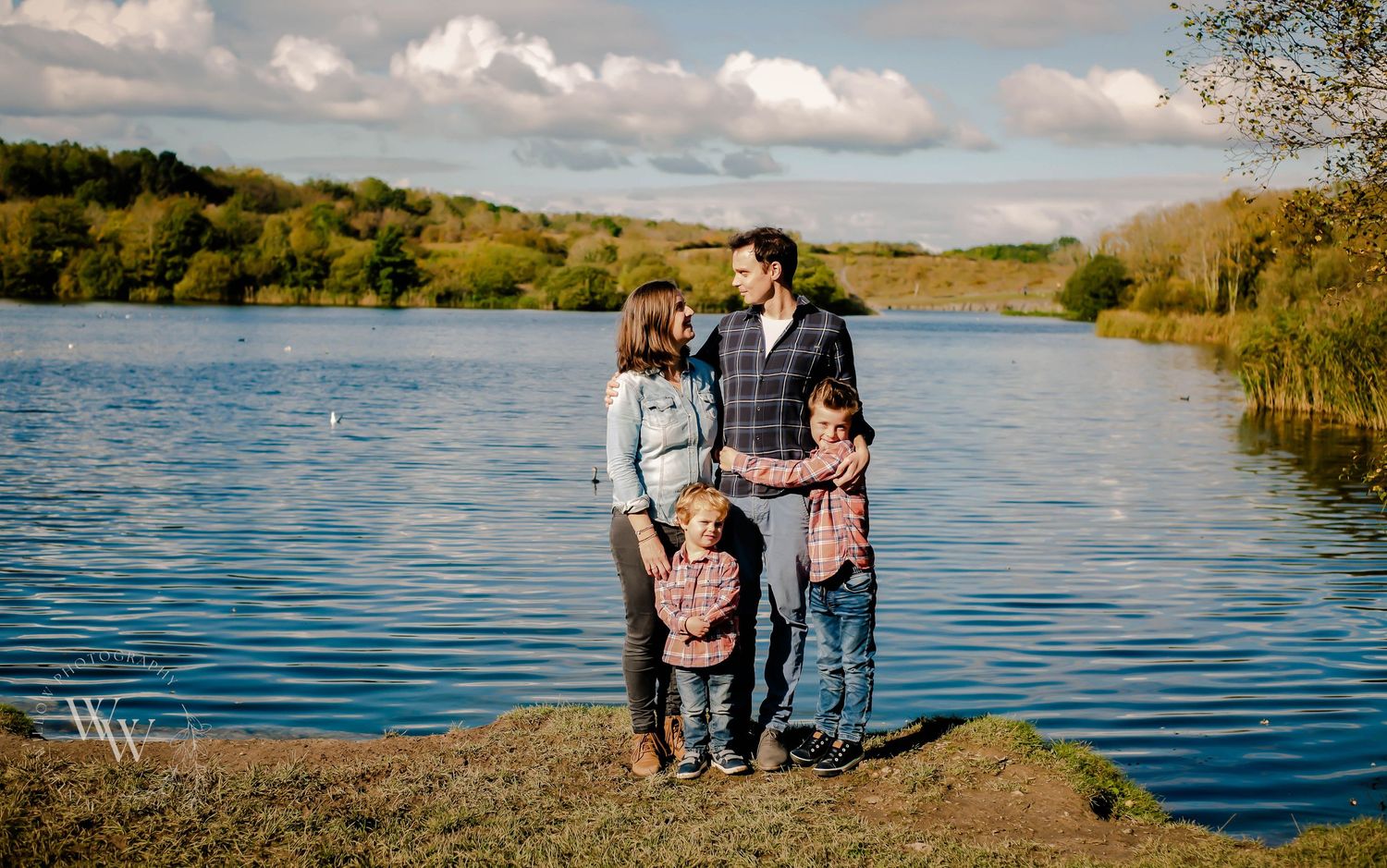 Family of four smiling together beside Cosmeston Lake in Penarth