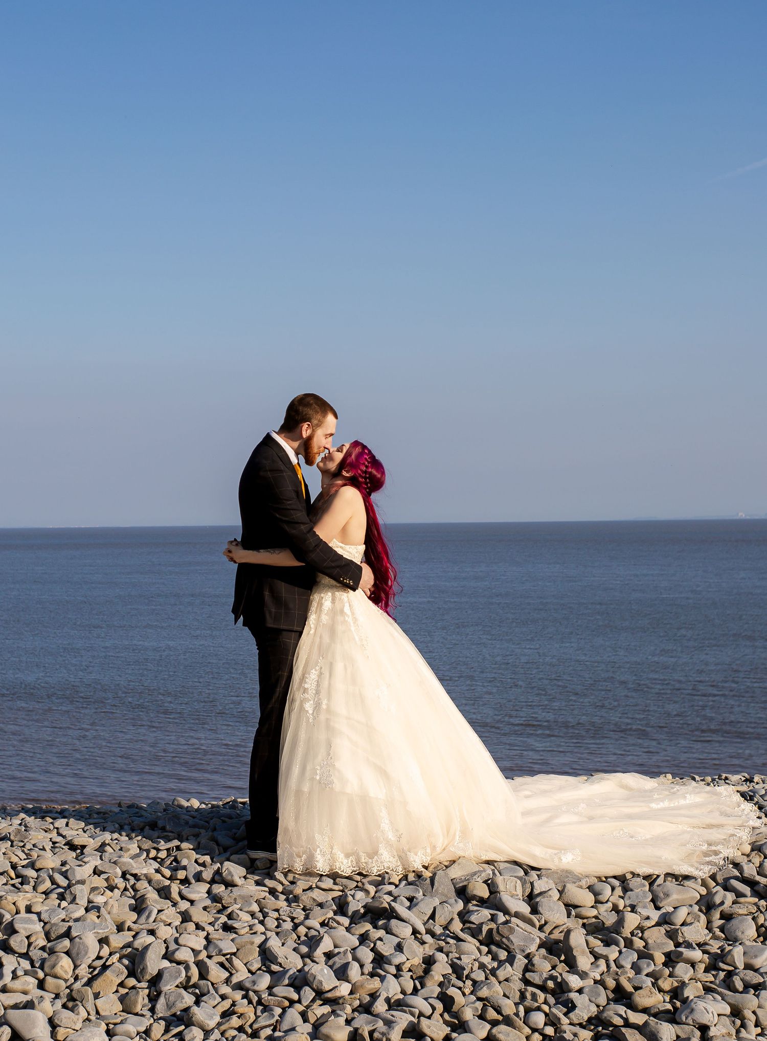 Newlyweds sharing a kiss beside the sea at Porthkerry Beach