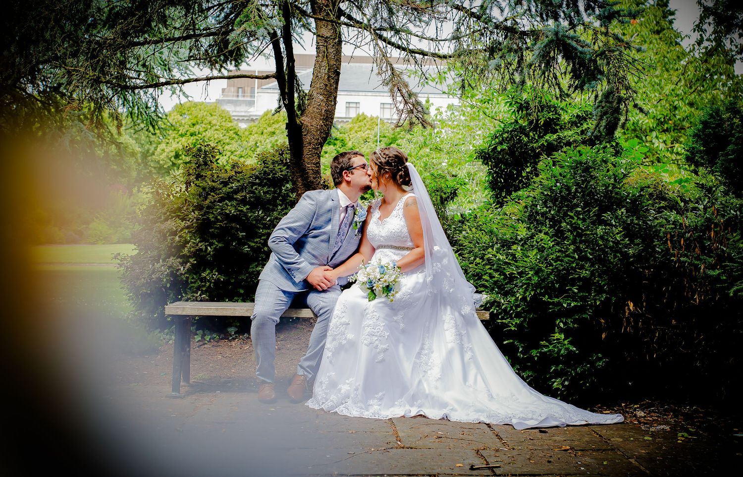 Bride and groom kissing on a garden bench