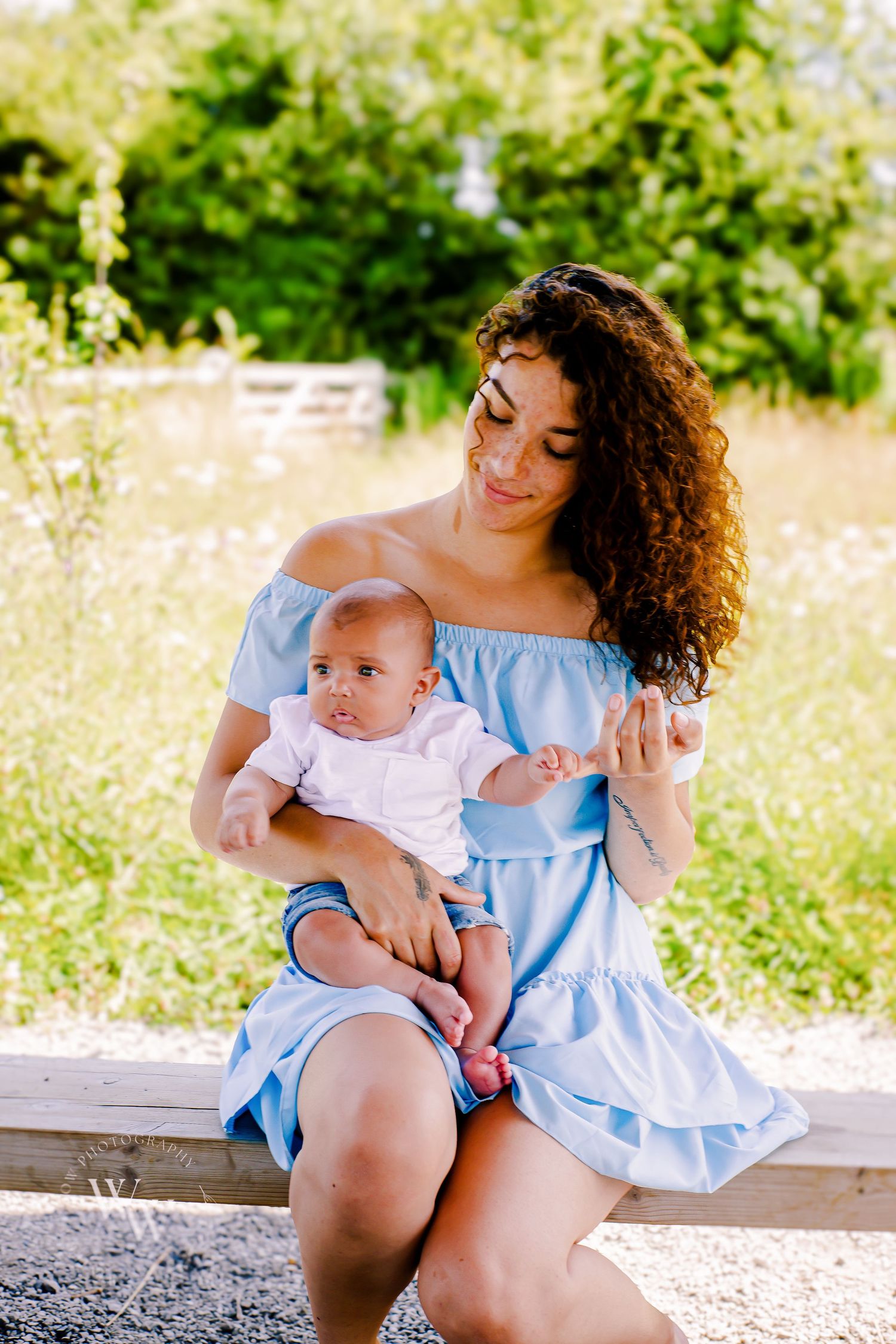 Mother cuddling her baby while seated beside a wildflower meadow at Cosmeston Lake, Penarth