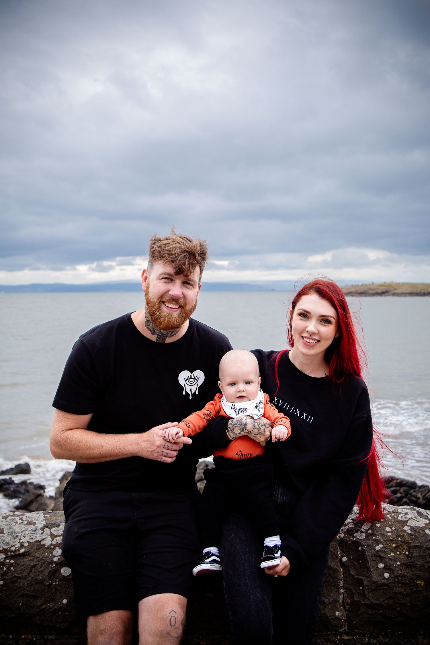 Mother and father holding their baby on the rocks at Barry Island