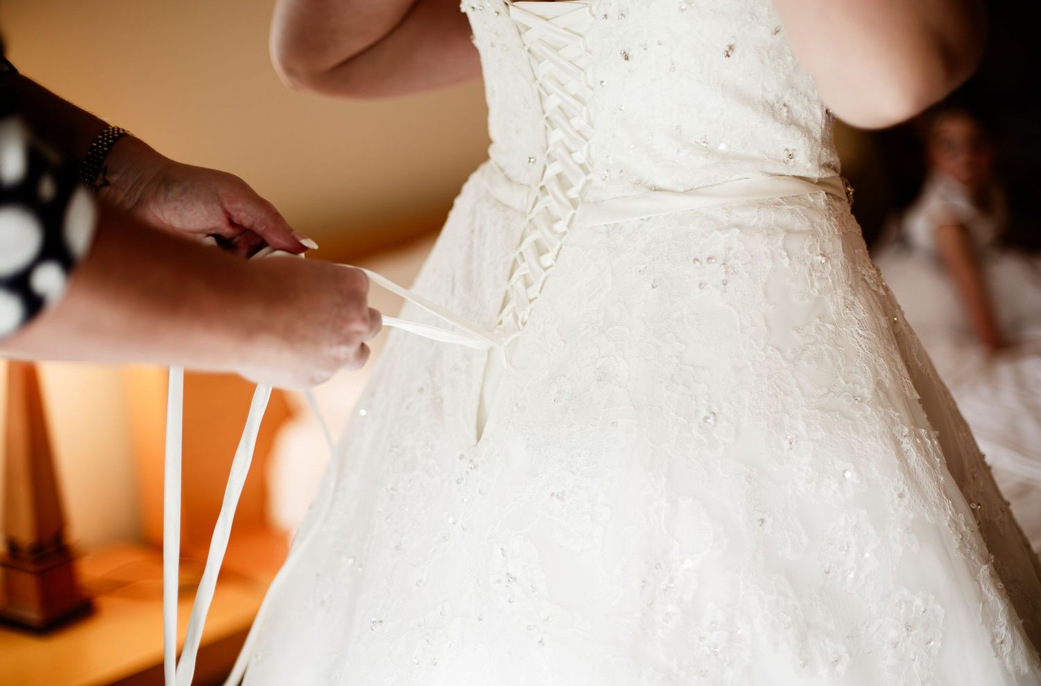 Close-up of a wedding dress being fastened during bridal preparations