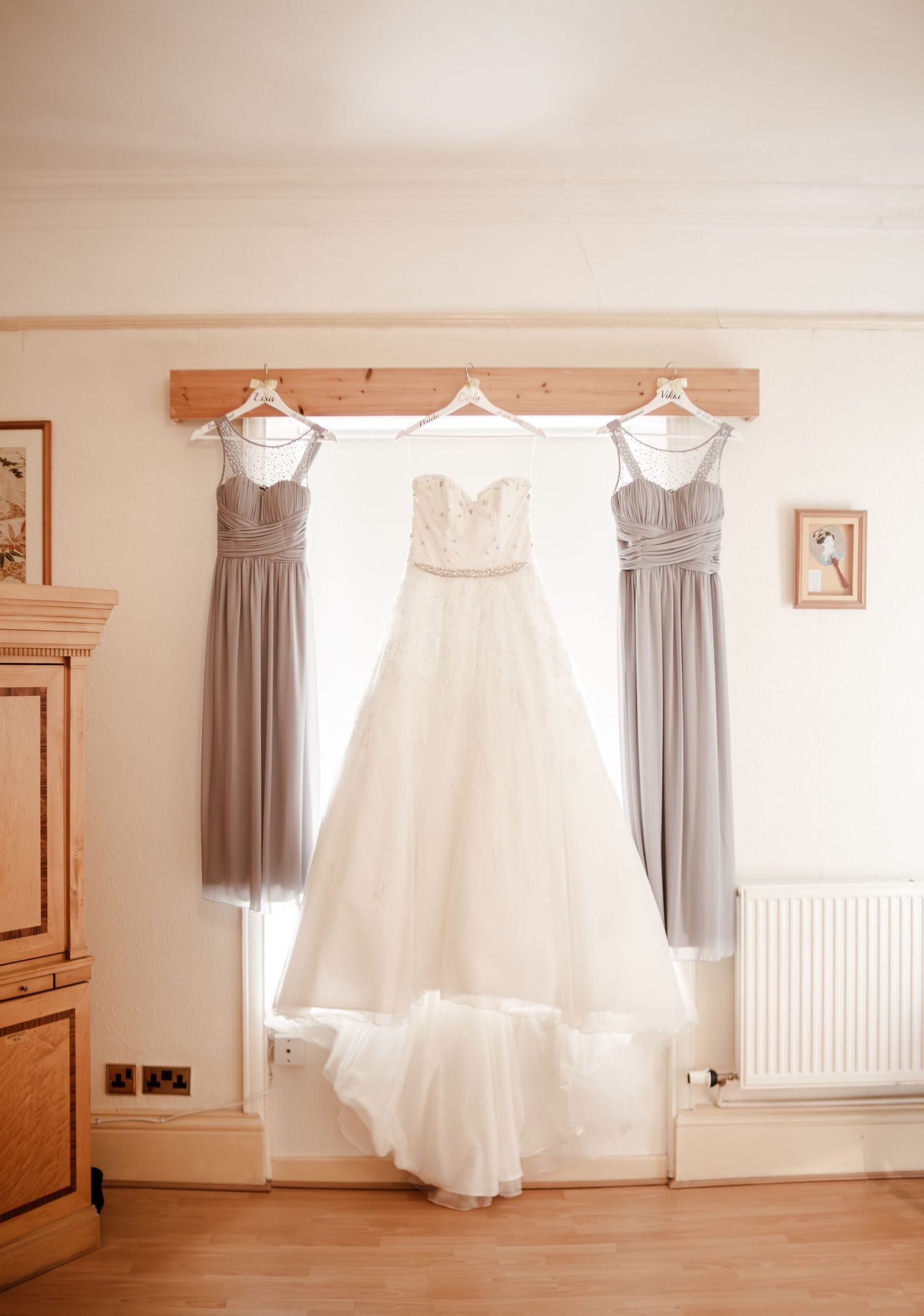 White wedding dress hanging in a softly lit bridal preparation room