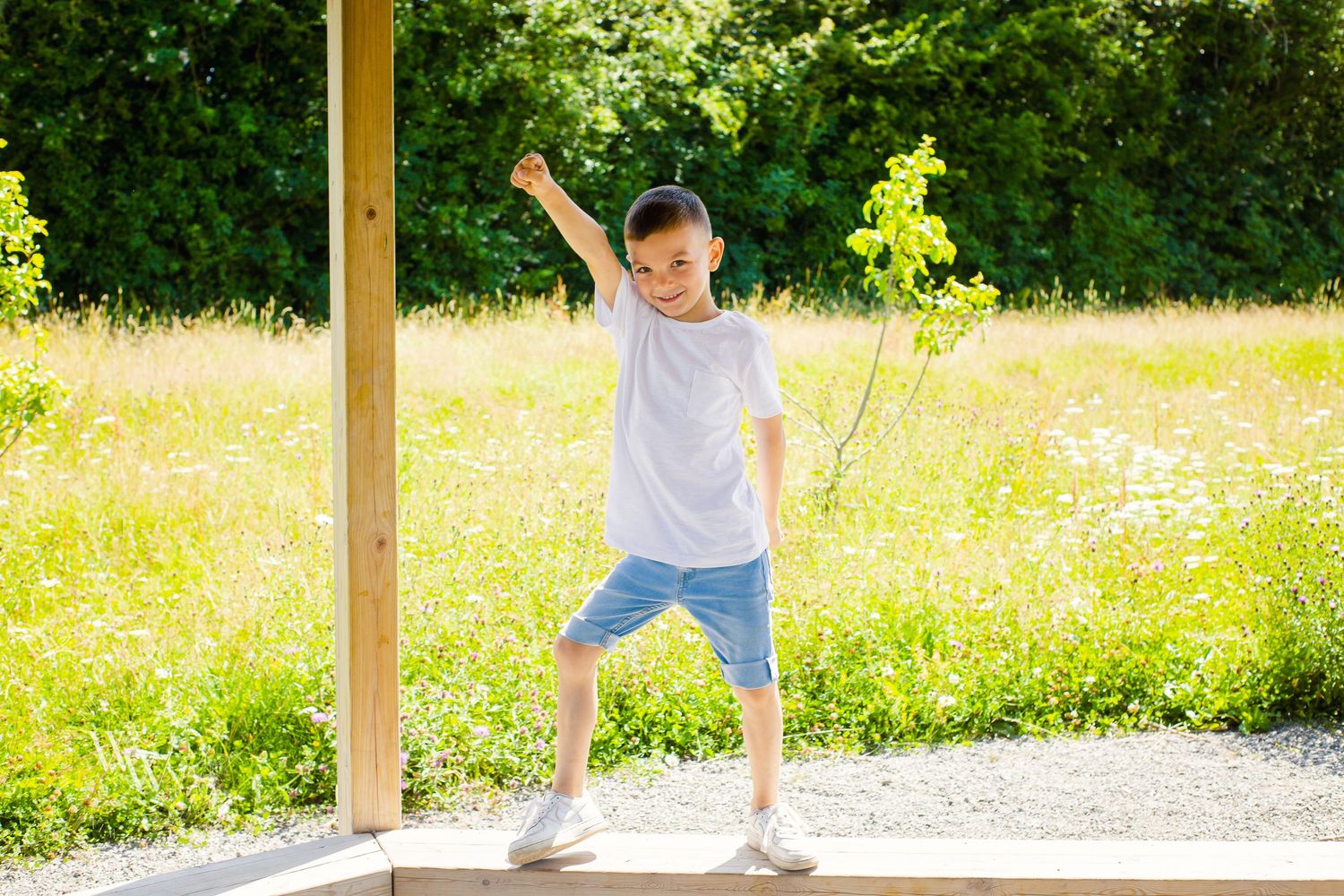 Young boy playfully balancing beside a summer meadow at Cosmeston Lake, Penarth